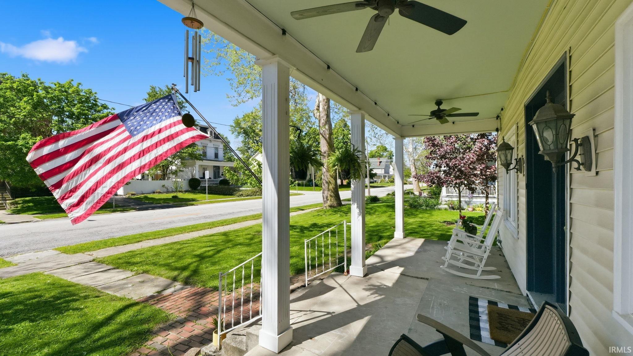 Covered front porch featuring concrete flooring, multiple ceiling fans, and porch lights