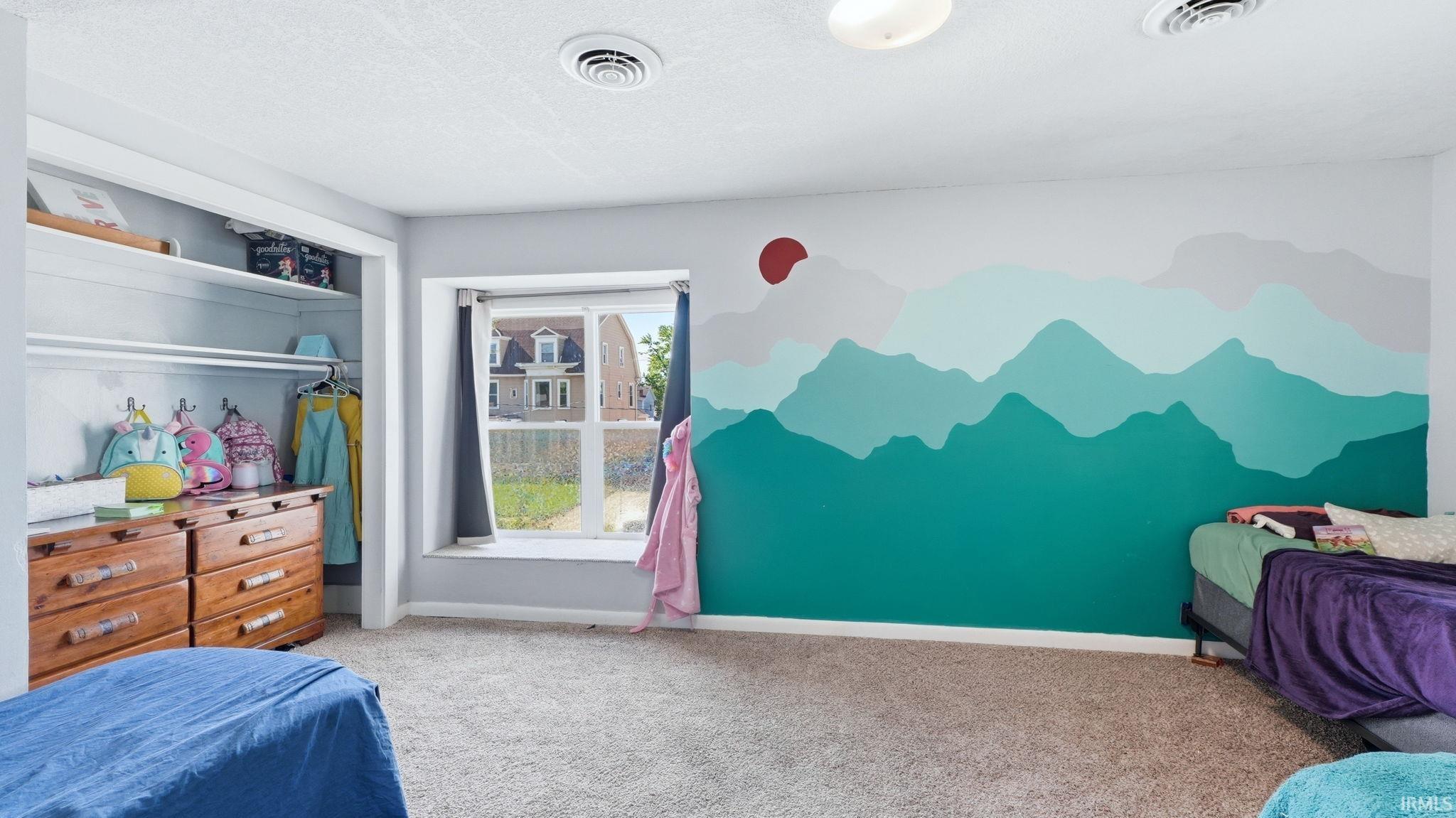 Carpeted room featuring a built-in closet with shelving and hanging rods