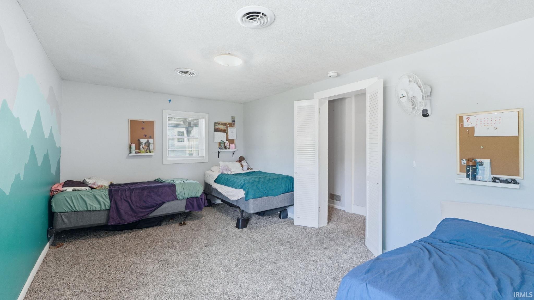 Carpeted room featuring a window, built-in closet with bi-fold louvered doors, and recessed lighting