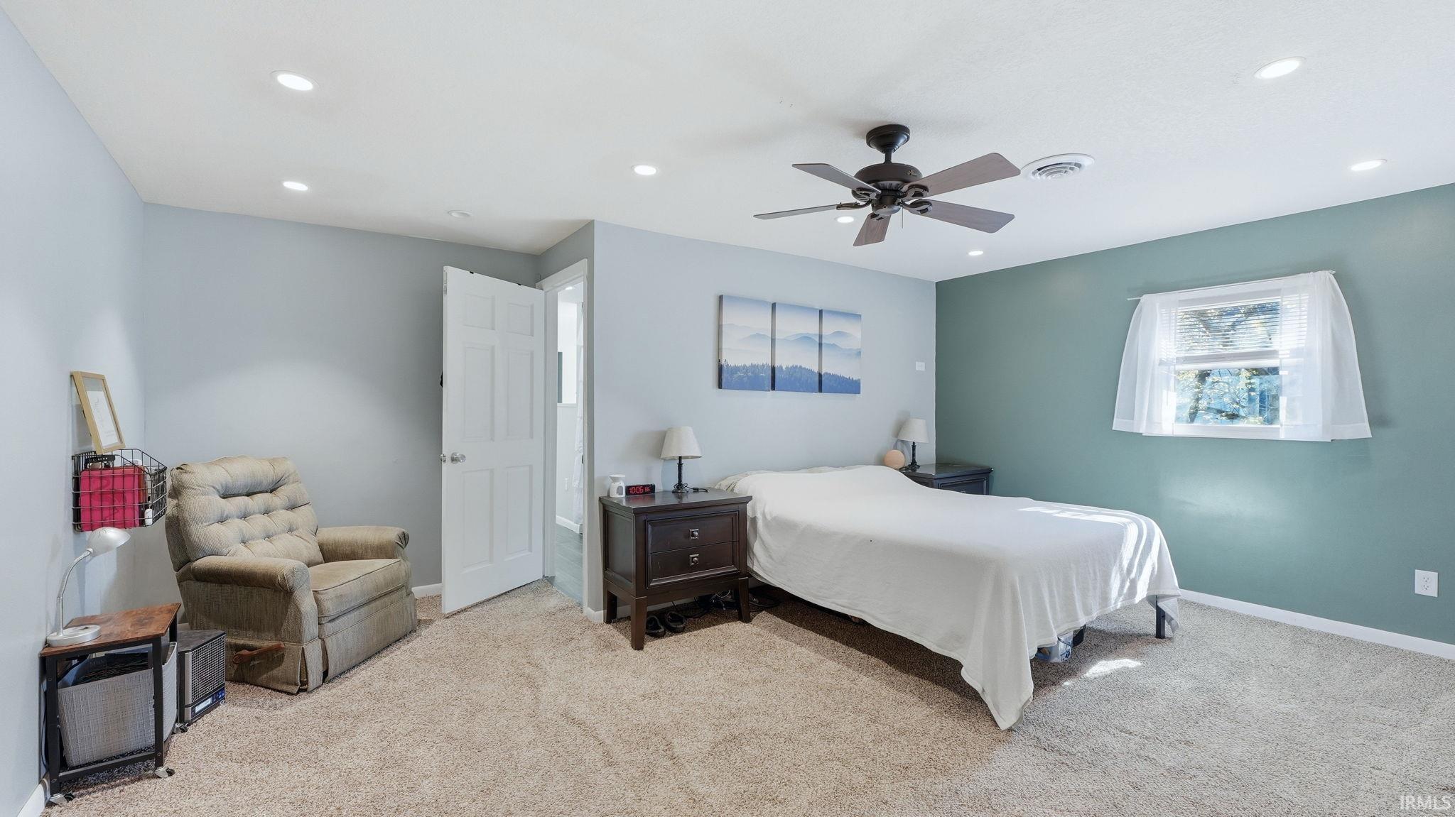 Carpeted room featuring a ceiling fan, recessed lighting, and a window with natural light