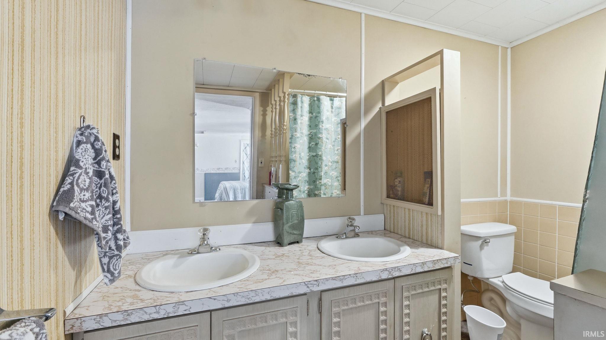Bathroom featuring a dual vanity with laminate countertops, two undermount sinks, and separate wall-mounted mirrors
