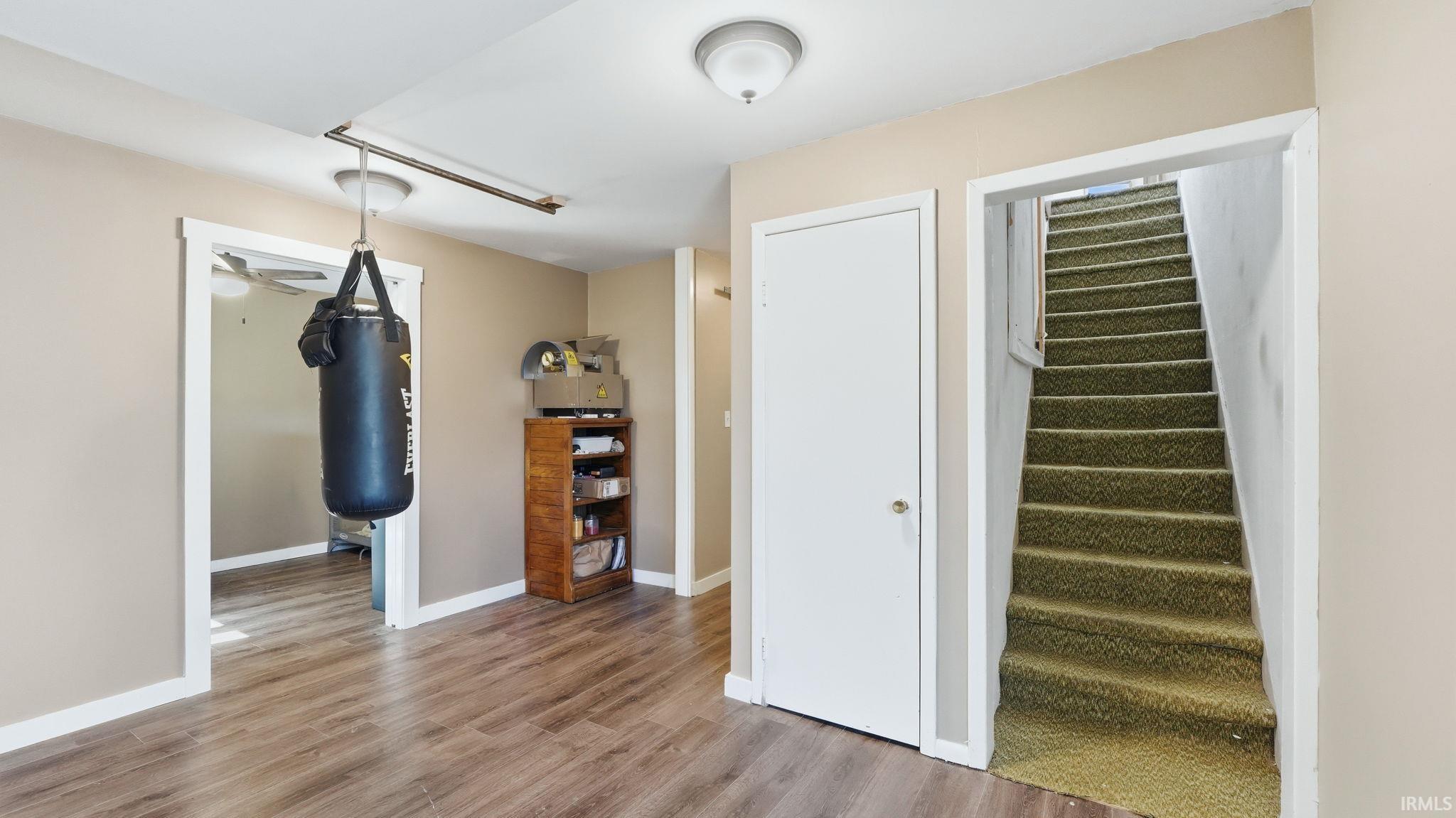 Versatile interior room featuring wood-finish flooring, neutral wall tones, and white trim