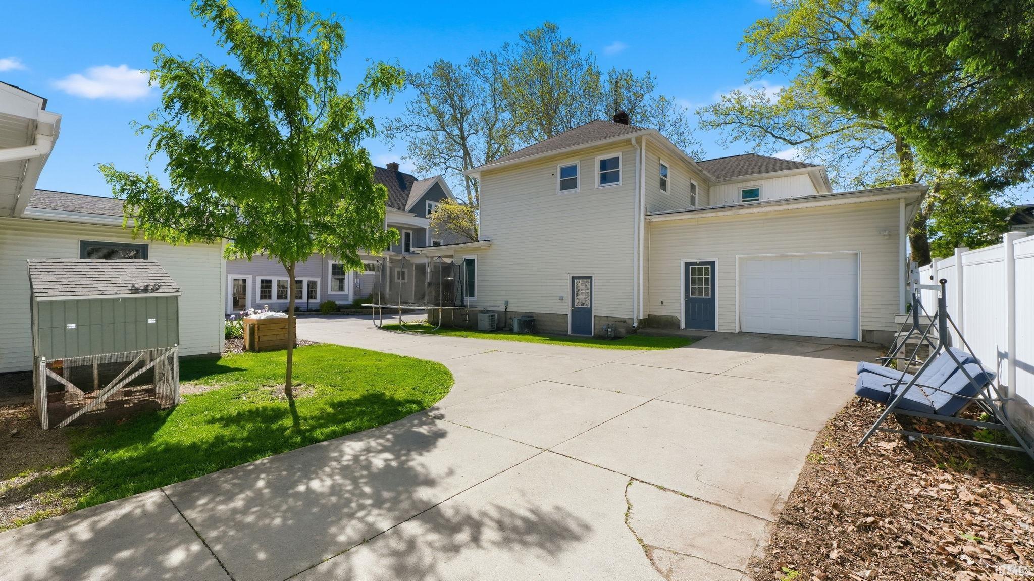 Expansive concrete driveway servicing a two-story residence with an attached garage featuring a white overhead door