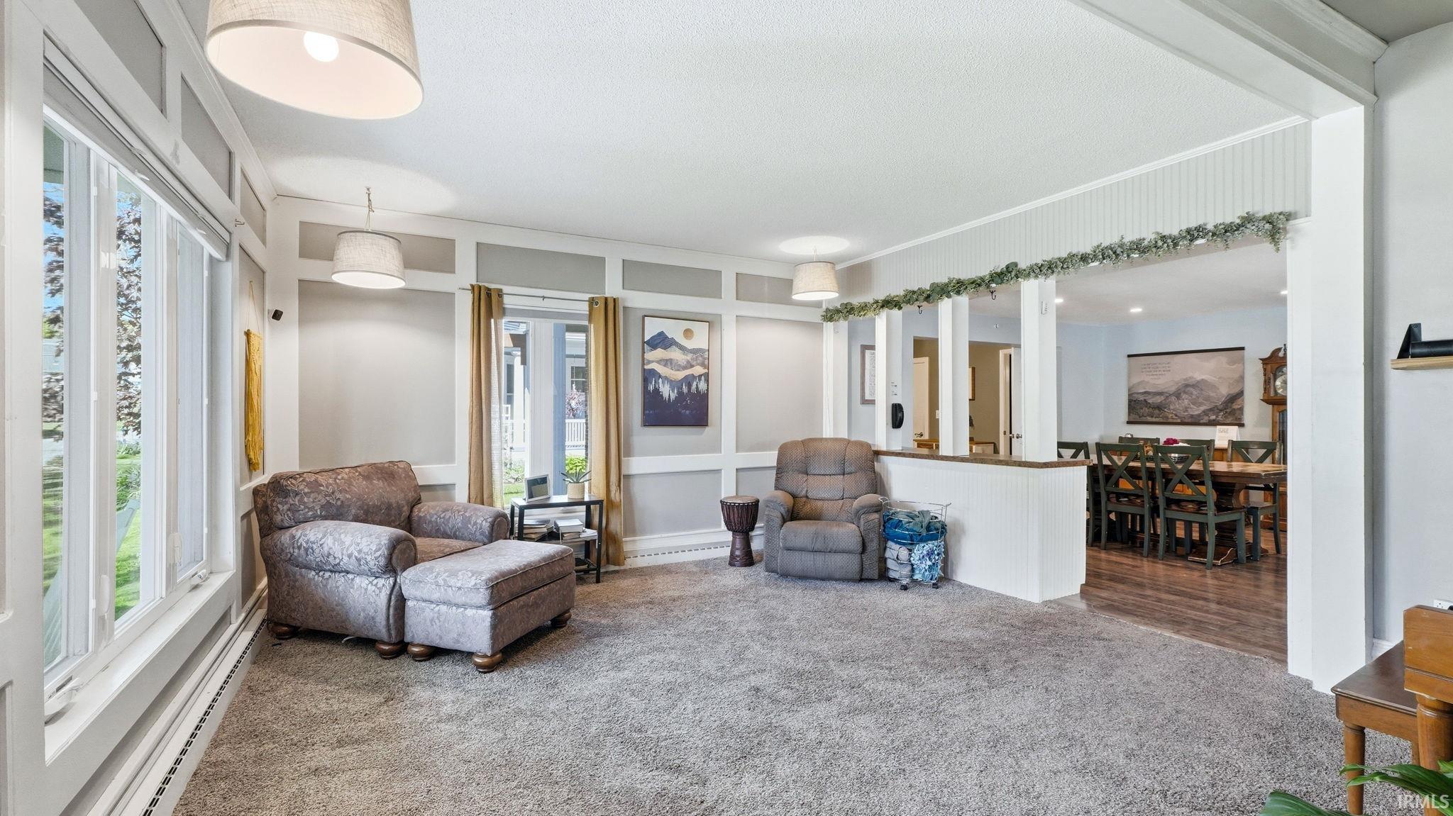 Carpeted living area featuring wainscoting and large picture windows