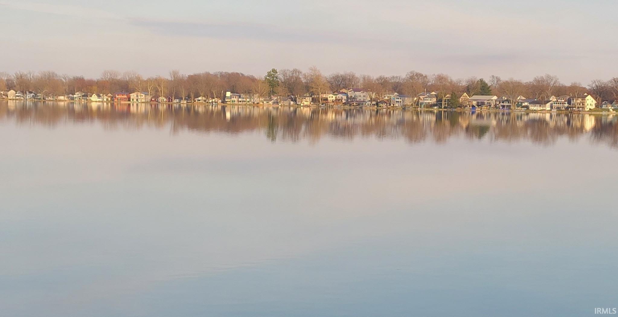 Waterfront properties featuring diverse architectural styles, mature trees, and calm water