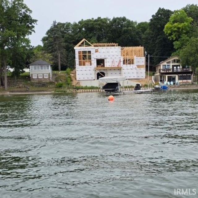 Waterfront property featuring a partially constructed structure, mature trees, and a private dock with a boat lift
