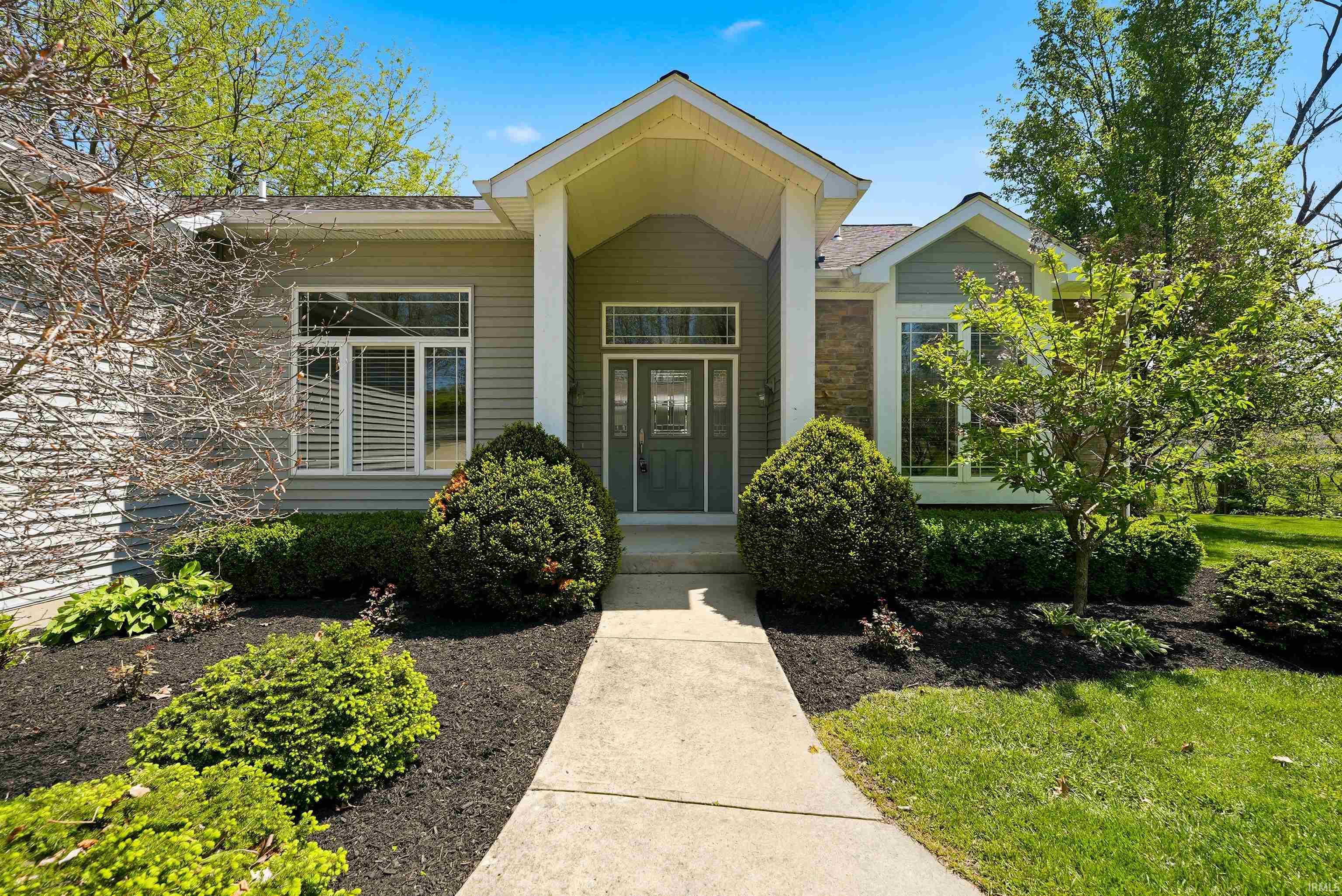 Inviting entry featuring a covered porch, stone facade accents, and decorative sidelights surrounding the front door