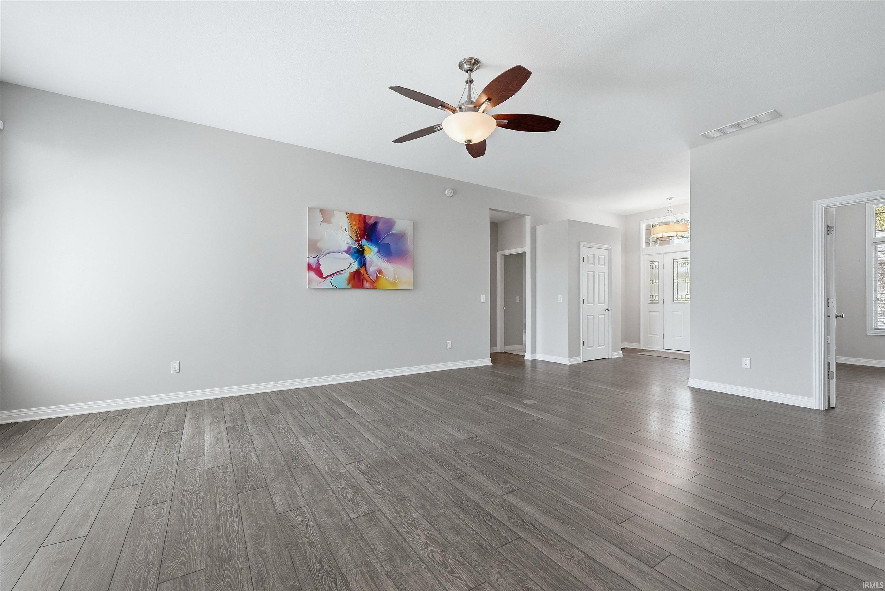 Spacious living area featuring wood-finish flooring, light gray wall tones, and white baseboards