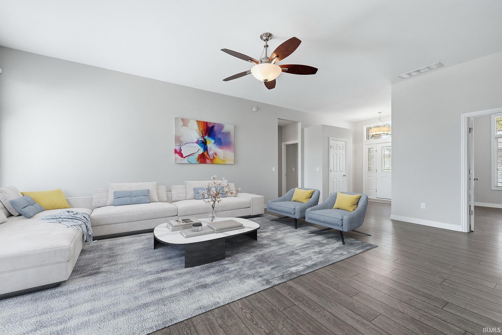 Spacious living area featuring wood-finish flooring, a ceiling fan with integrated lighting, and neutral wall tones