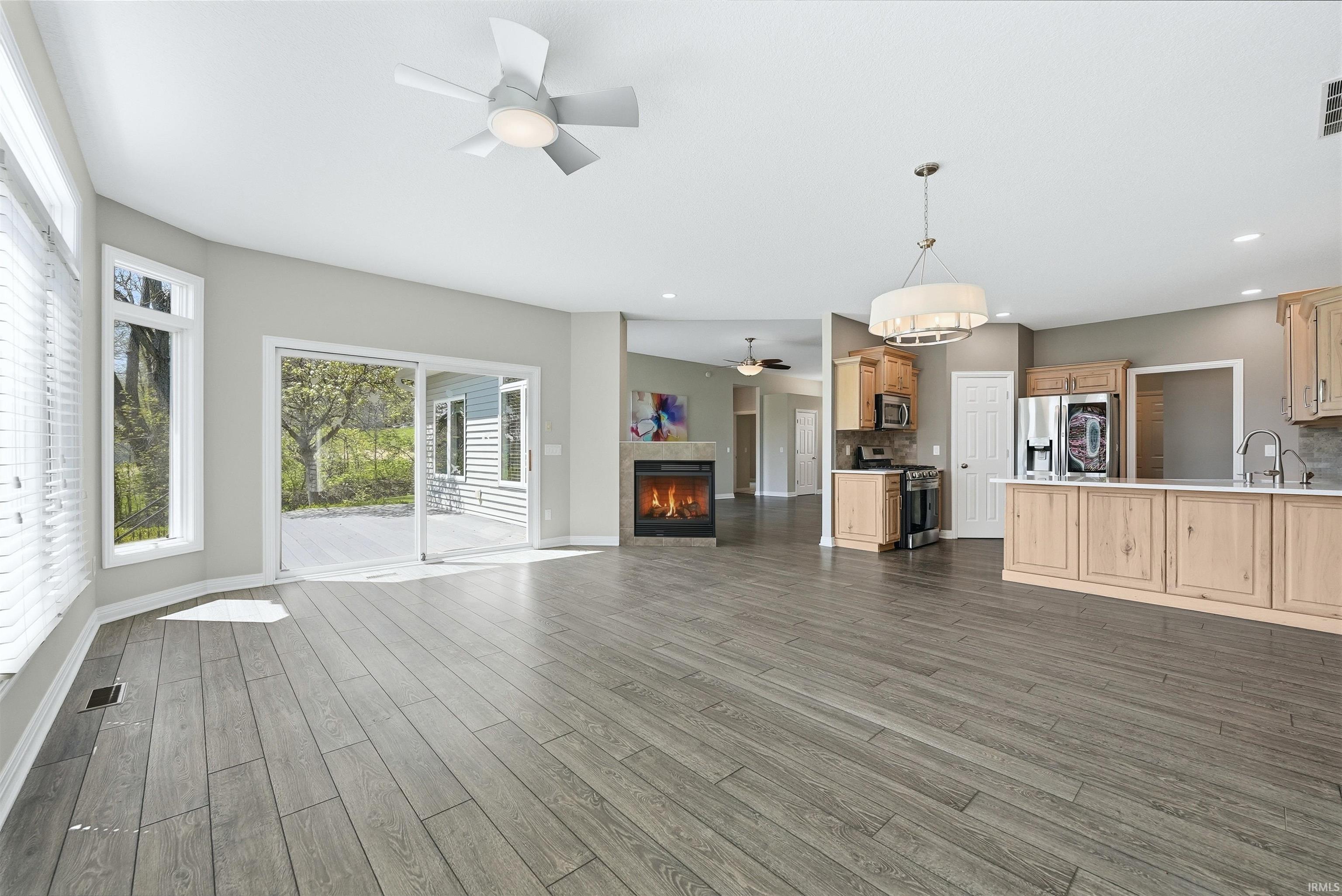 Spacious open-concept living area featuring wood-finish flooring, a contemporary fireplace, and a kitchen island with seating