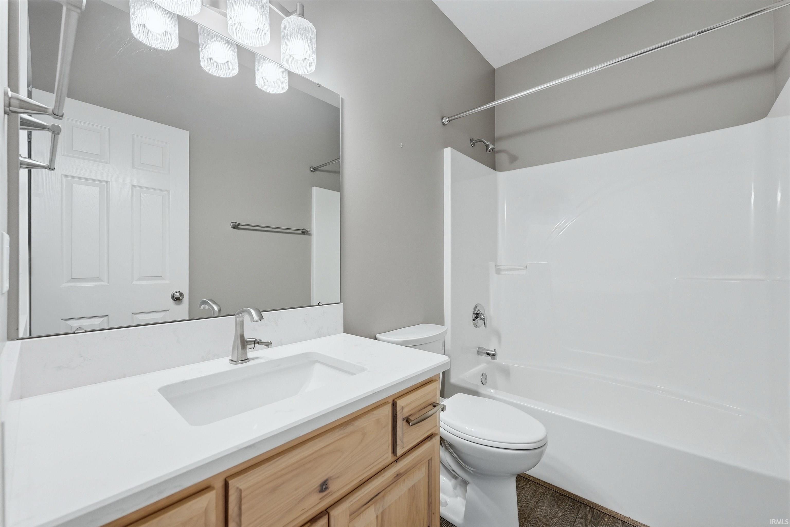 Bathroom featuring a light wood-finish vanity with a white countertop and integrated sink, brushed nickel faucet, and an overhead vanity light fixture