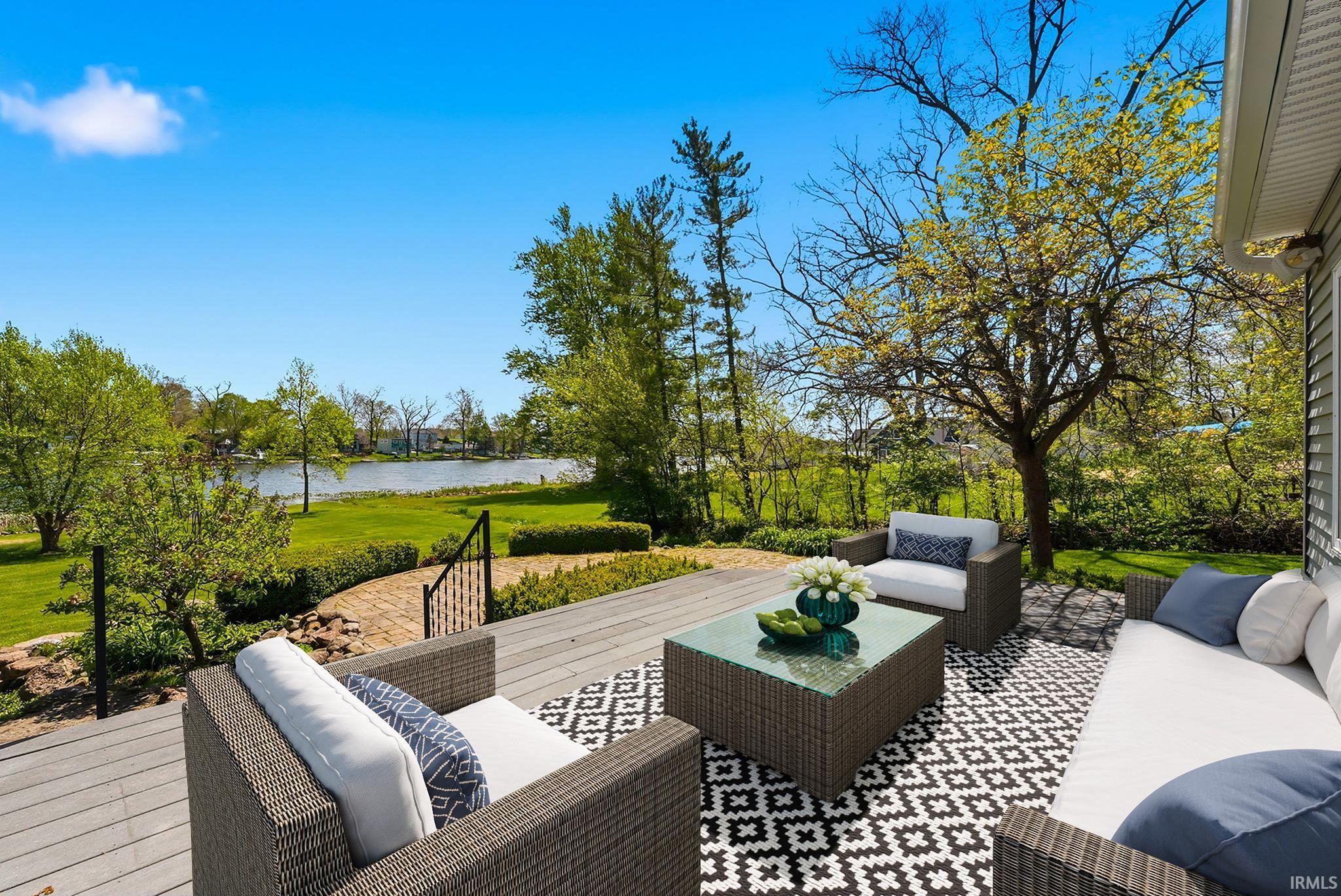 Spacious outdoor deck with composite decking, black metal railings, and a brick paver pathway leading to a large lawn