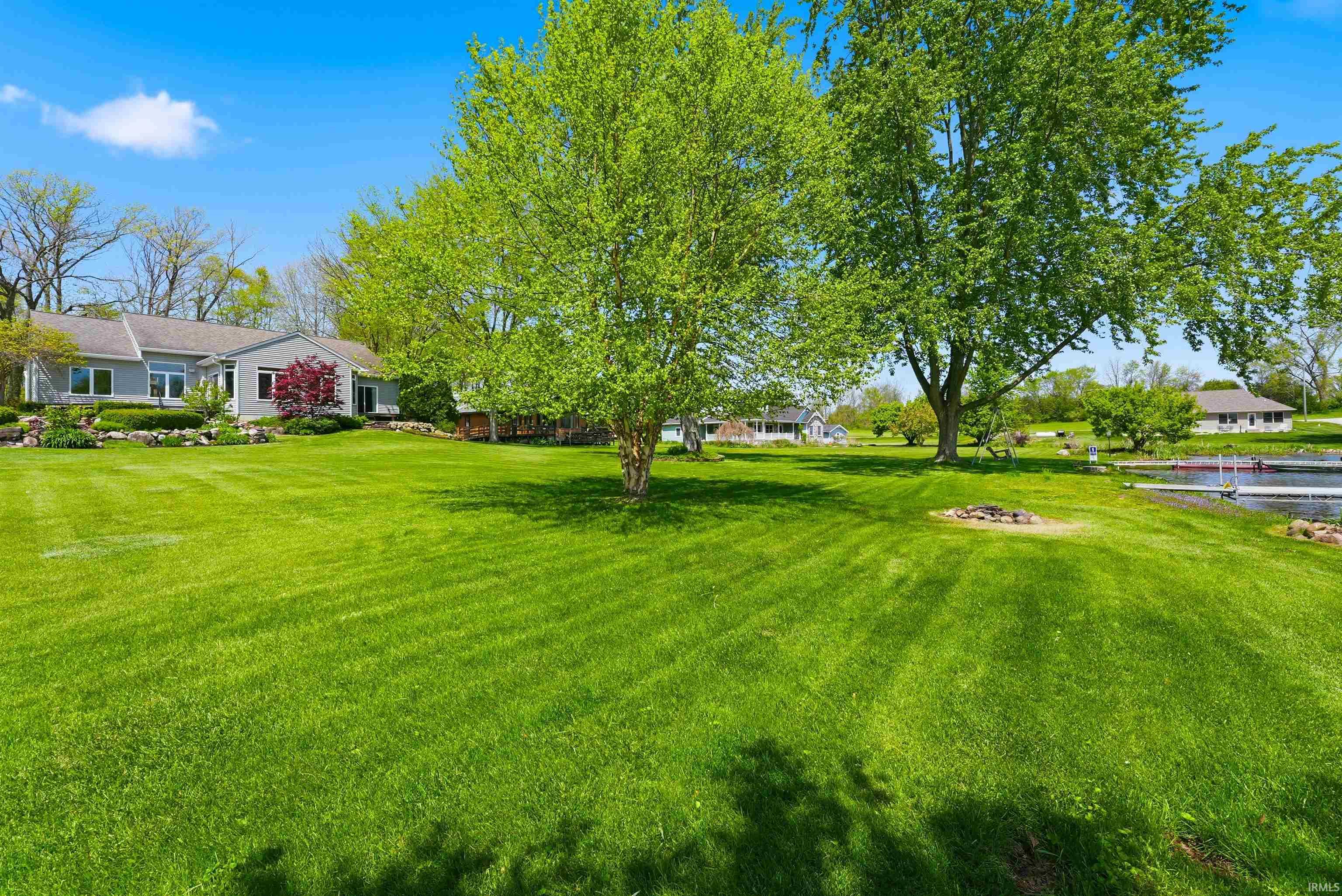 Expansive green lawn with mature trees and a waterfront presence