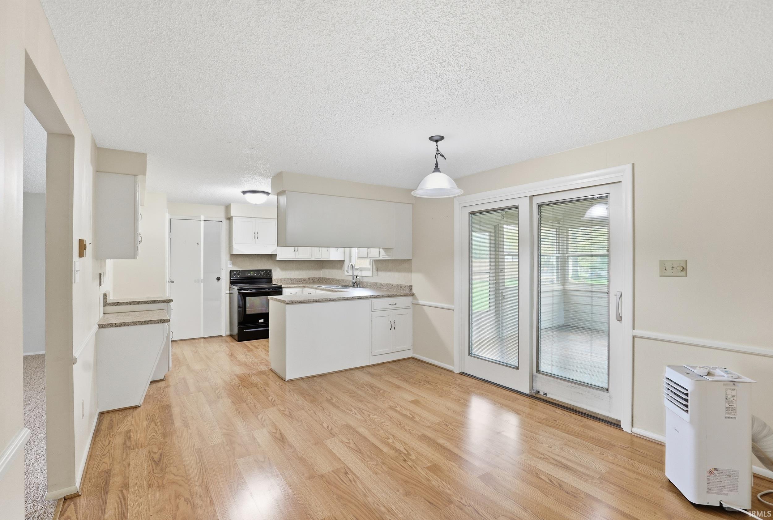 Kitchen and dining area featuring wood-finish flooring, white cabinetry, and light-toned countertops