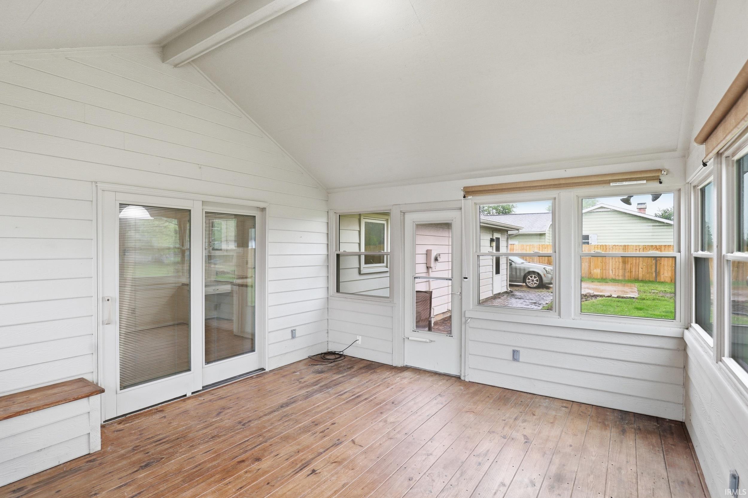Enclosed porch featuring wood-finish flooring, white shiplap walls, multiple windows, a paneled ceiling, and sliding glass doors