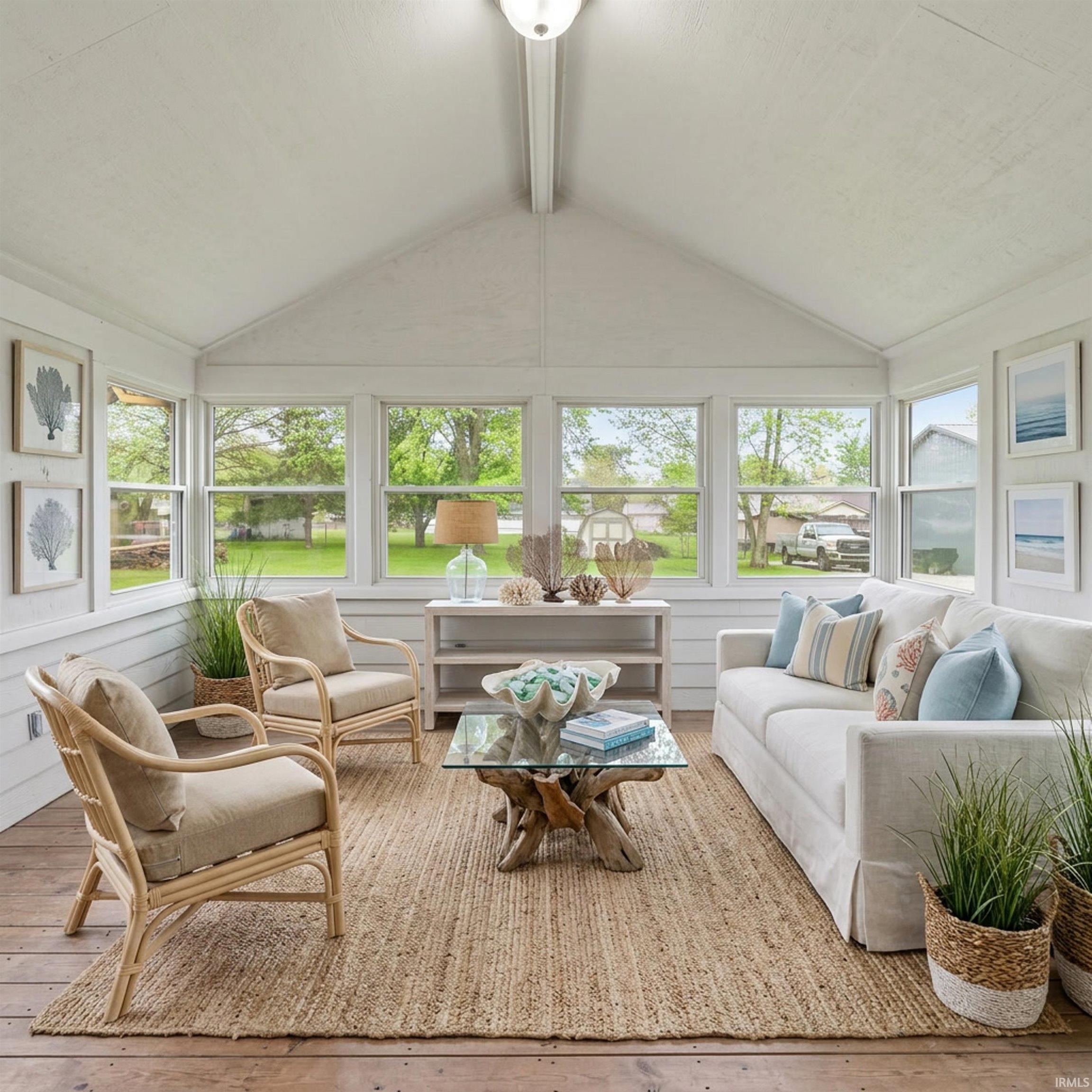 Enclosed porch with multiple picture windows, vaulted ceiling, wood-finish flooring, and shiplap walls