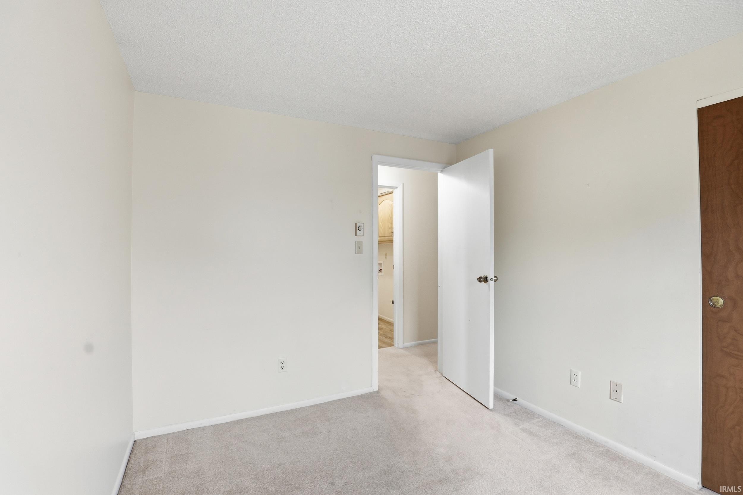 Carpeted room with neutral wall tones and white baseboards
