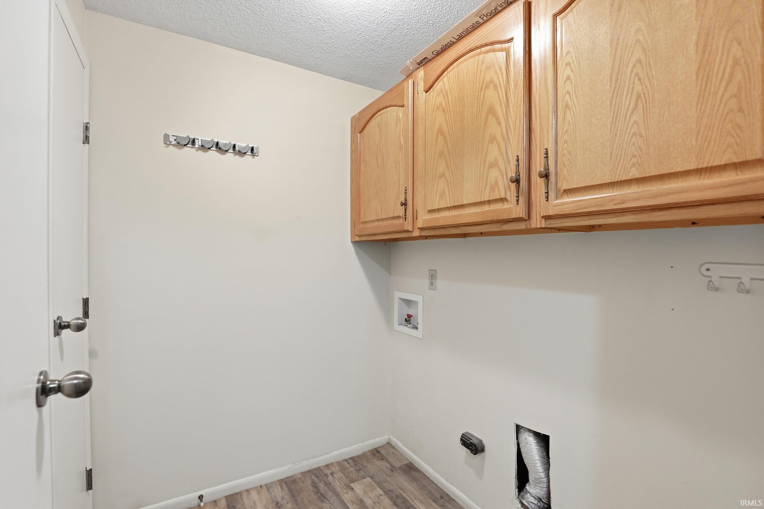 Utility room featuring wood-finish flooring and light-toned walls