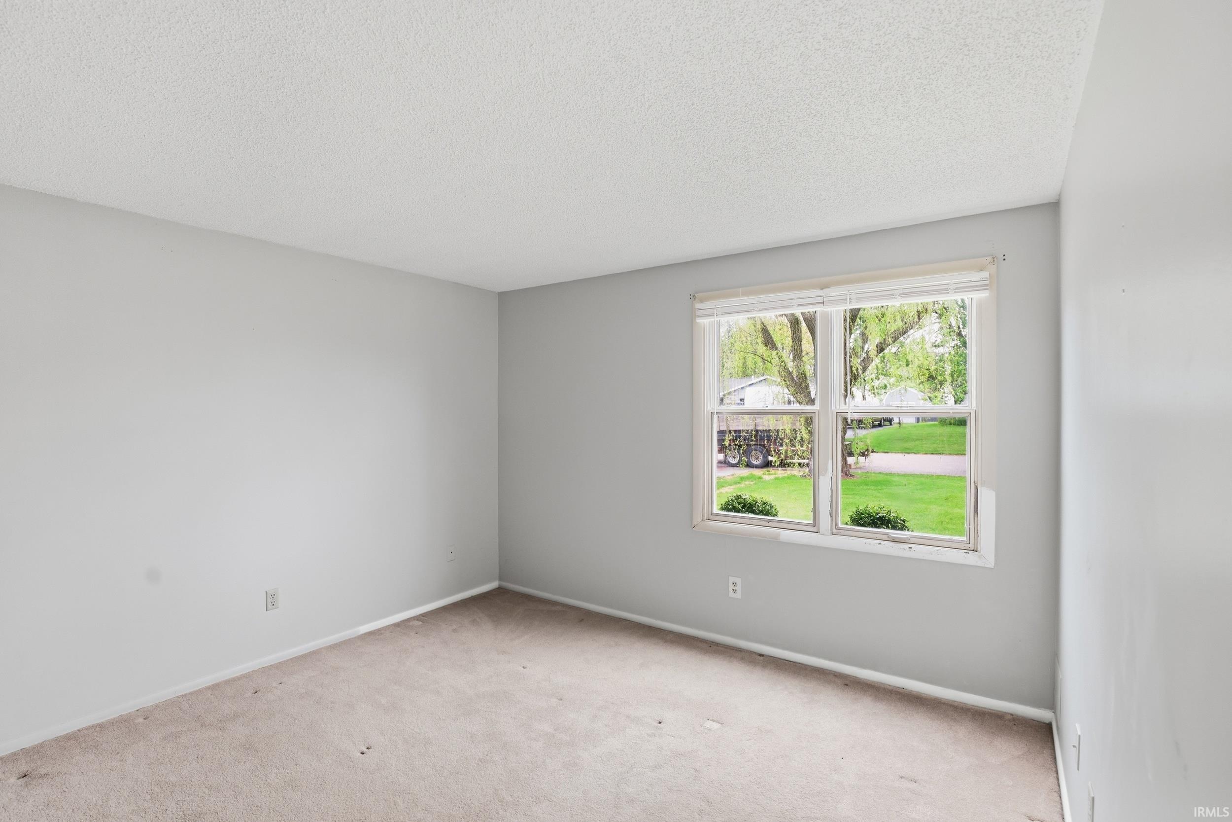 Room featuring carpet flooring, light gray walls, and a textured ceiling