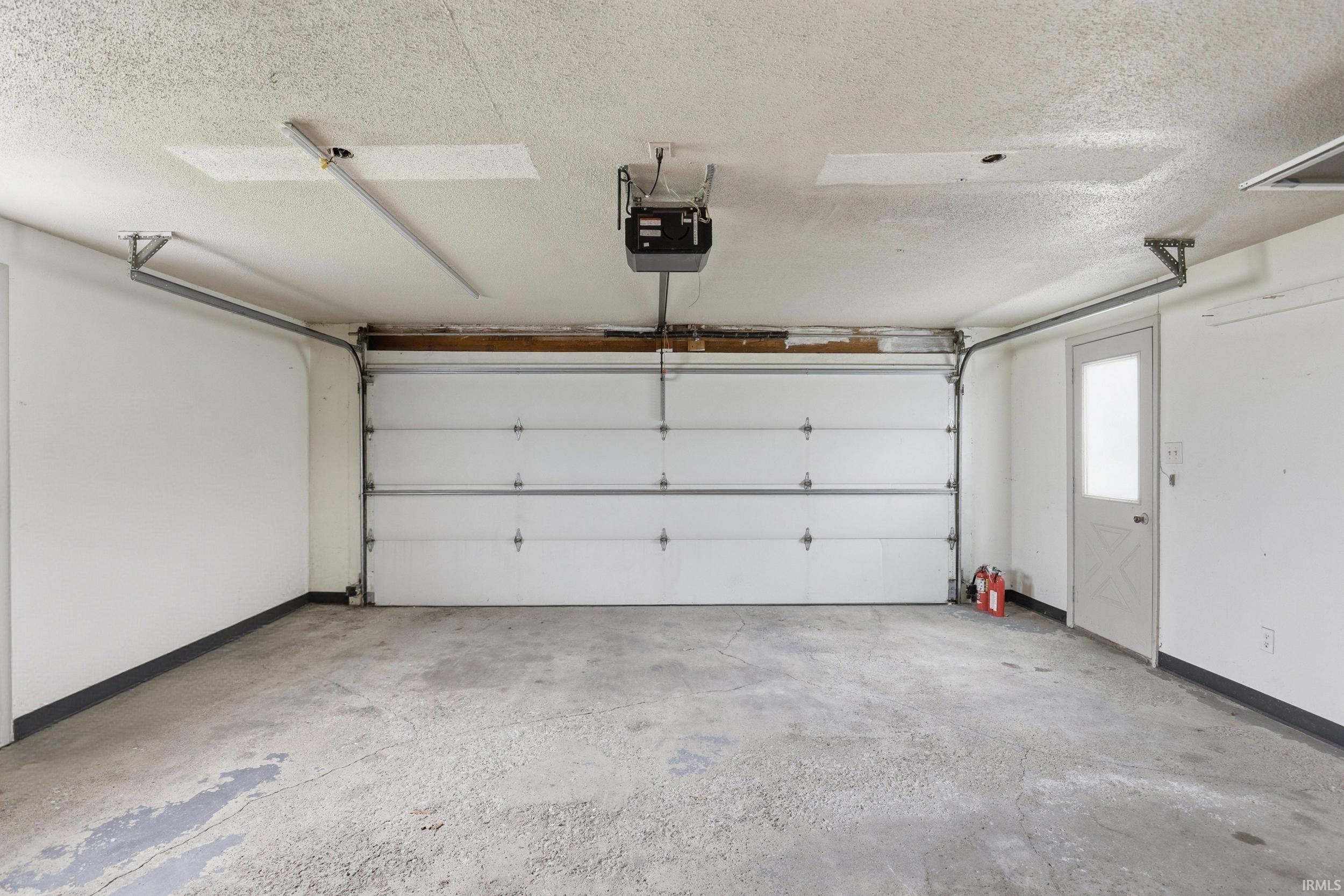 Spacious garage featuring a concrete floor, white walls, and an automatic overhead door