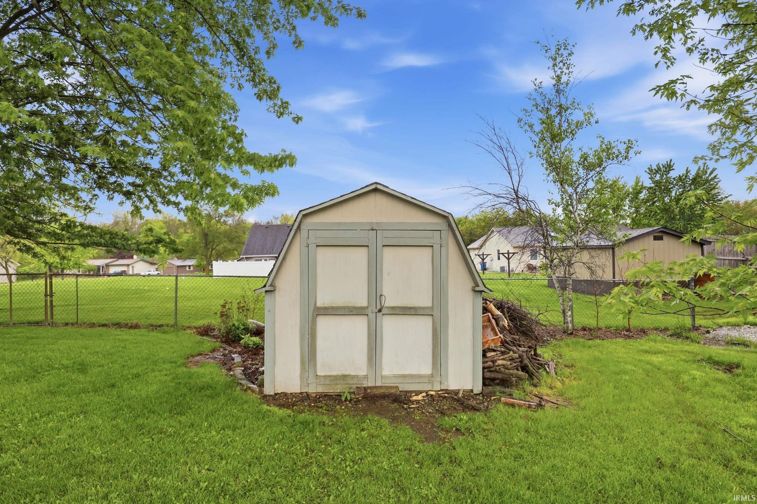 Detached storage shed featuring double barn doors and a gambrel roofline