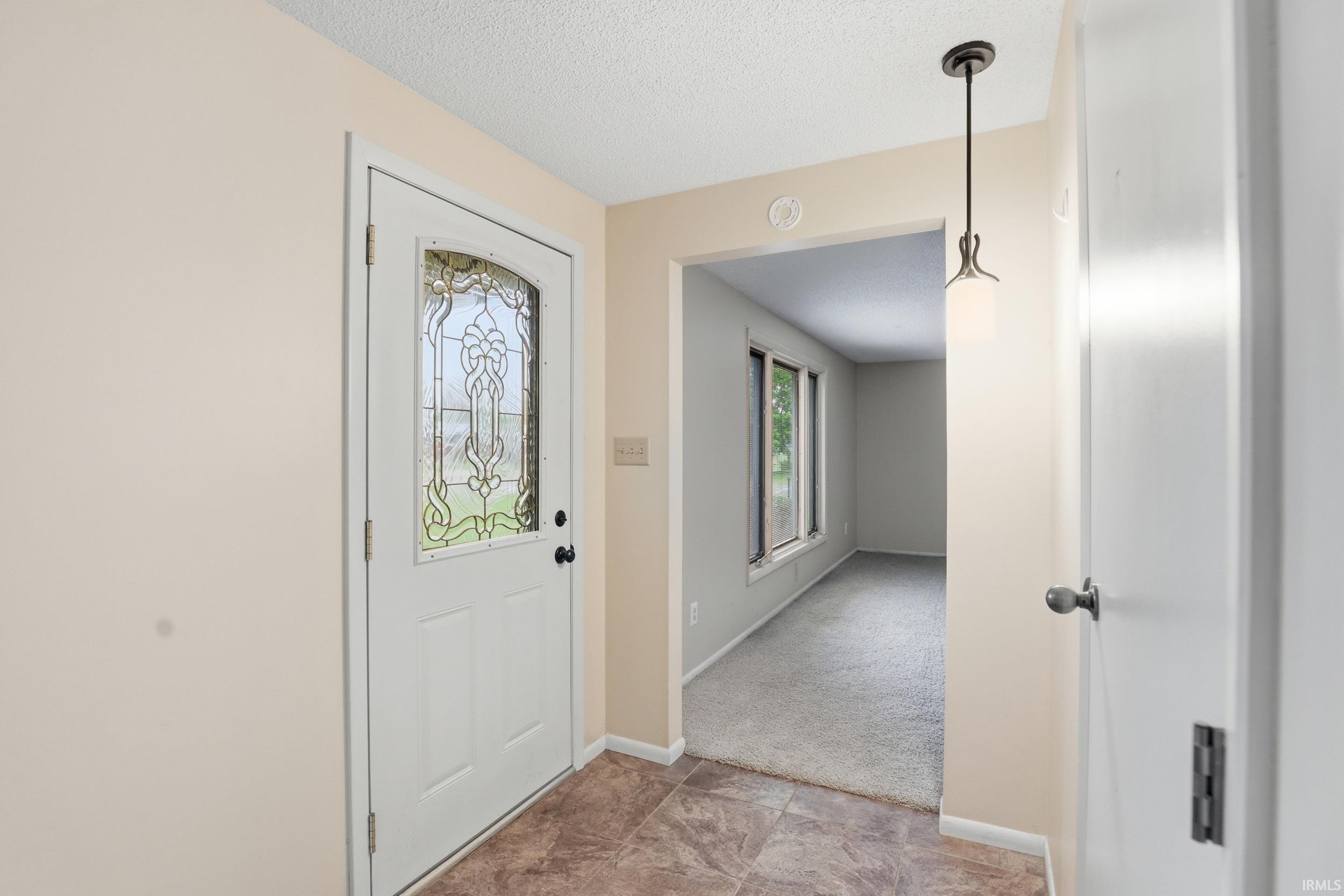 Entryway featuring a decorative glass-paneled door, tile flooring, and a contemporary pendant light fixture