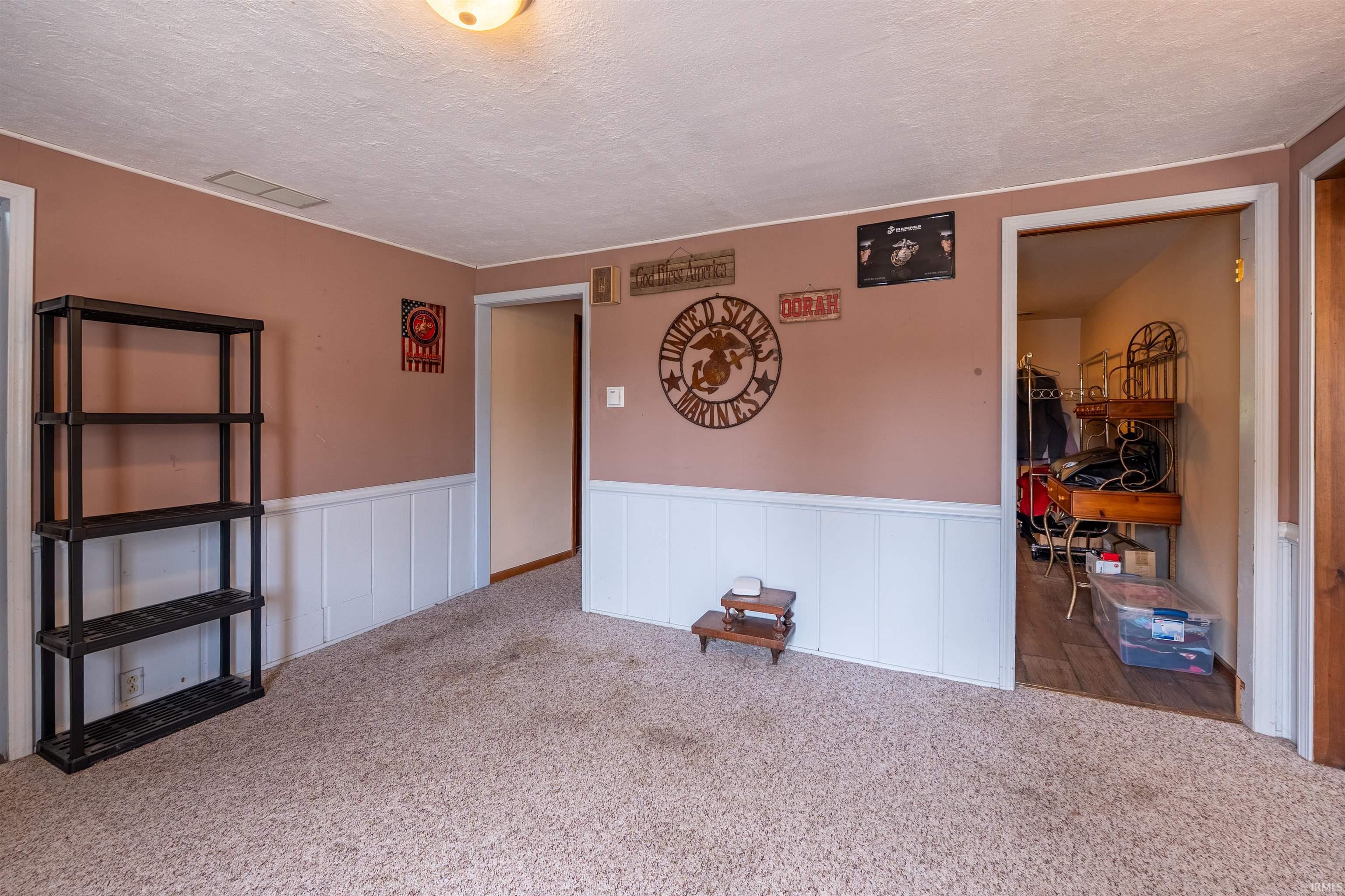 Carpeted room featuring a white wainscoting and light brown walls