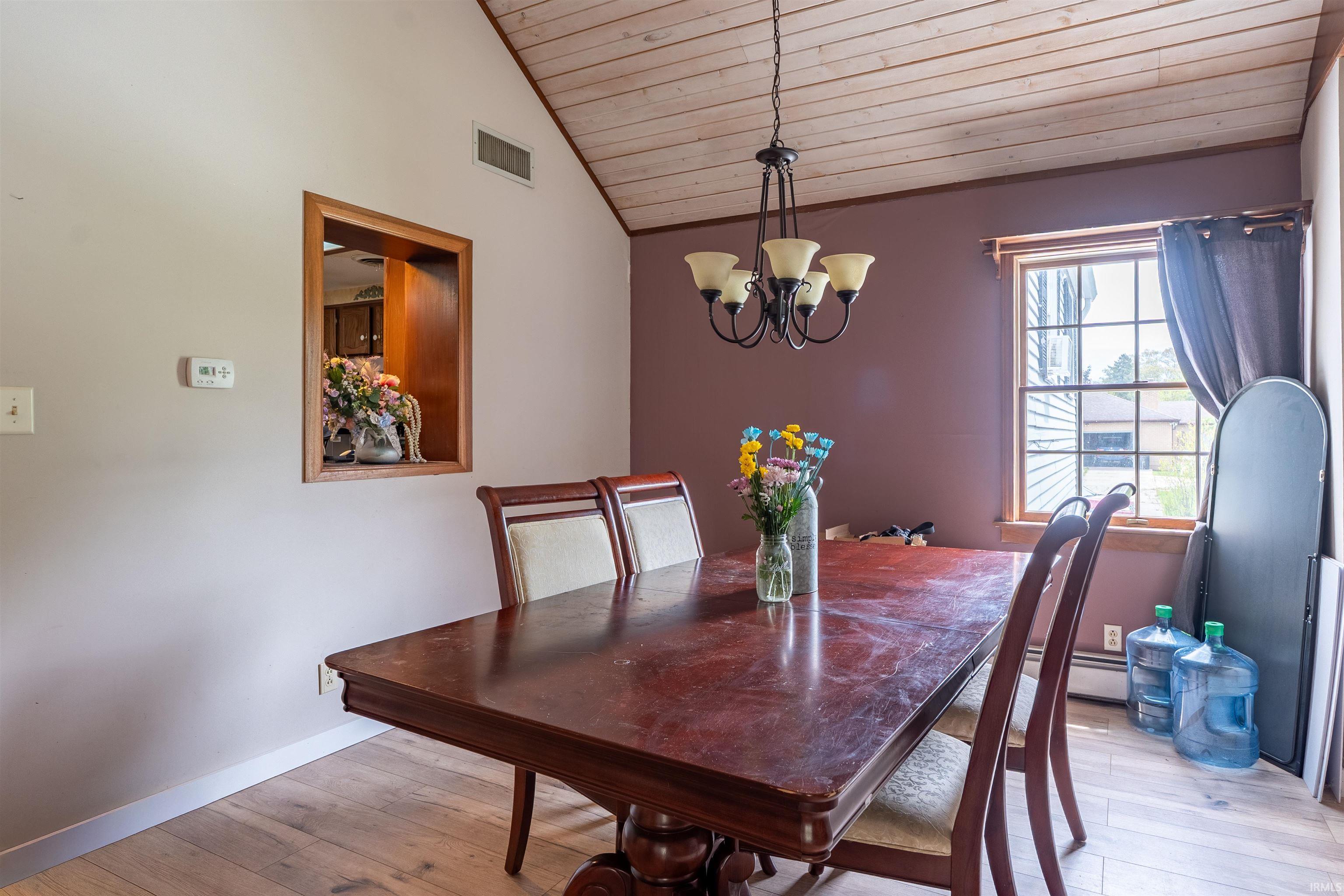 Dining area featuring a vaulted wood-paneled ceiling, wood-finish flooring, and a decorative chandelier