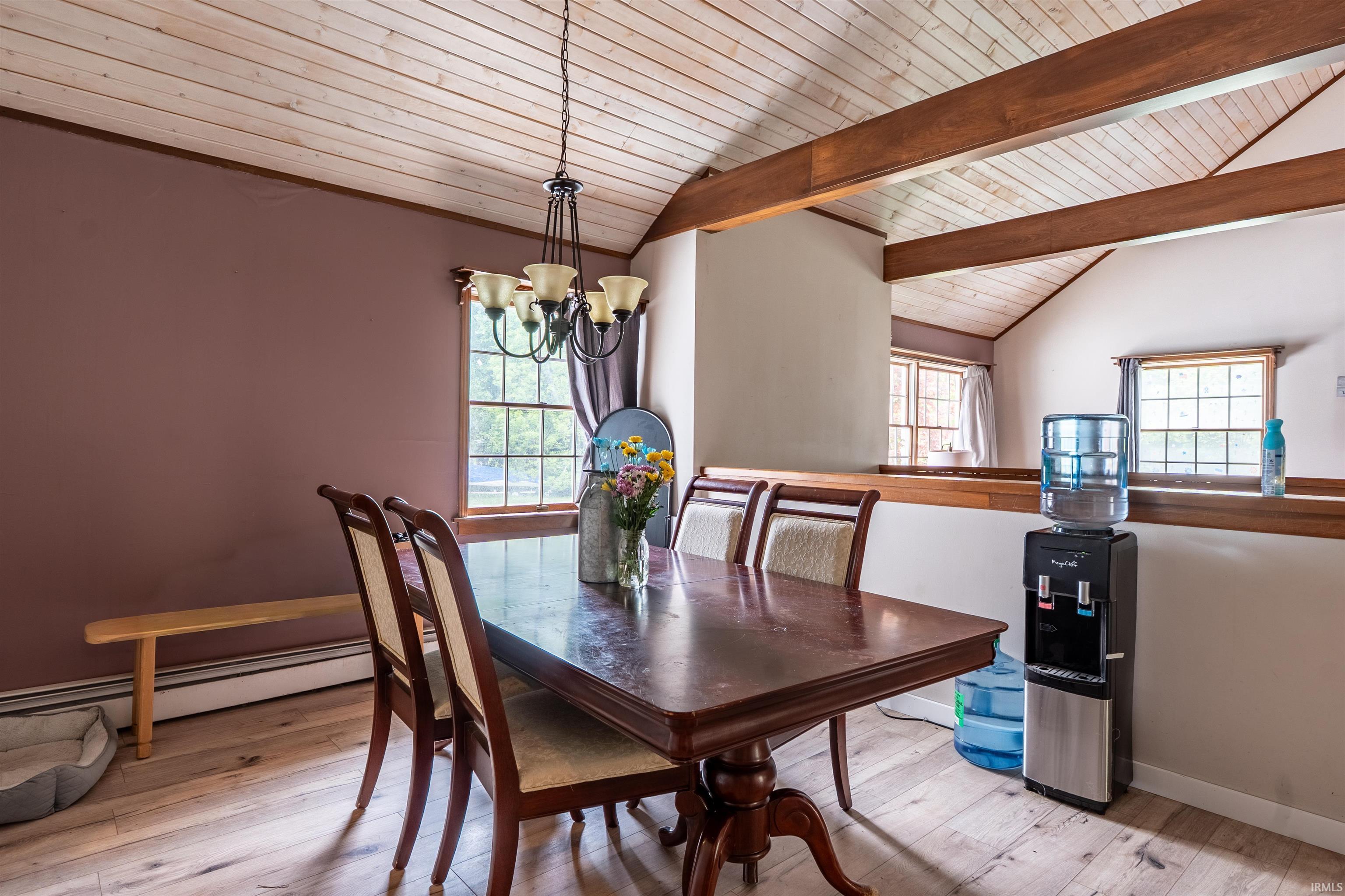 Dining area featuring a vaulted wood-plank ceiling with exposed wood beams, plank flooring, and a chandelier lighting fixture