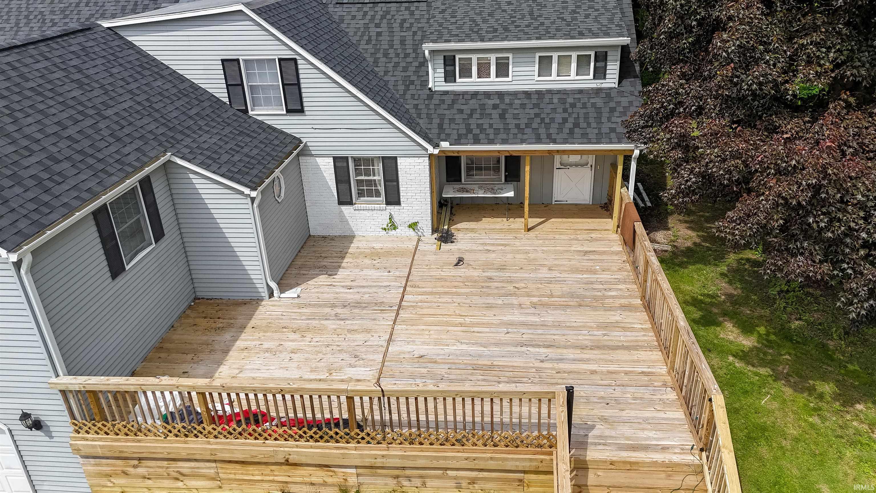 Expansive multi-level wood deck featuring a covered porch area and wood railings