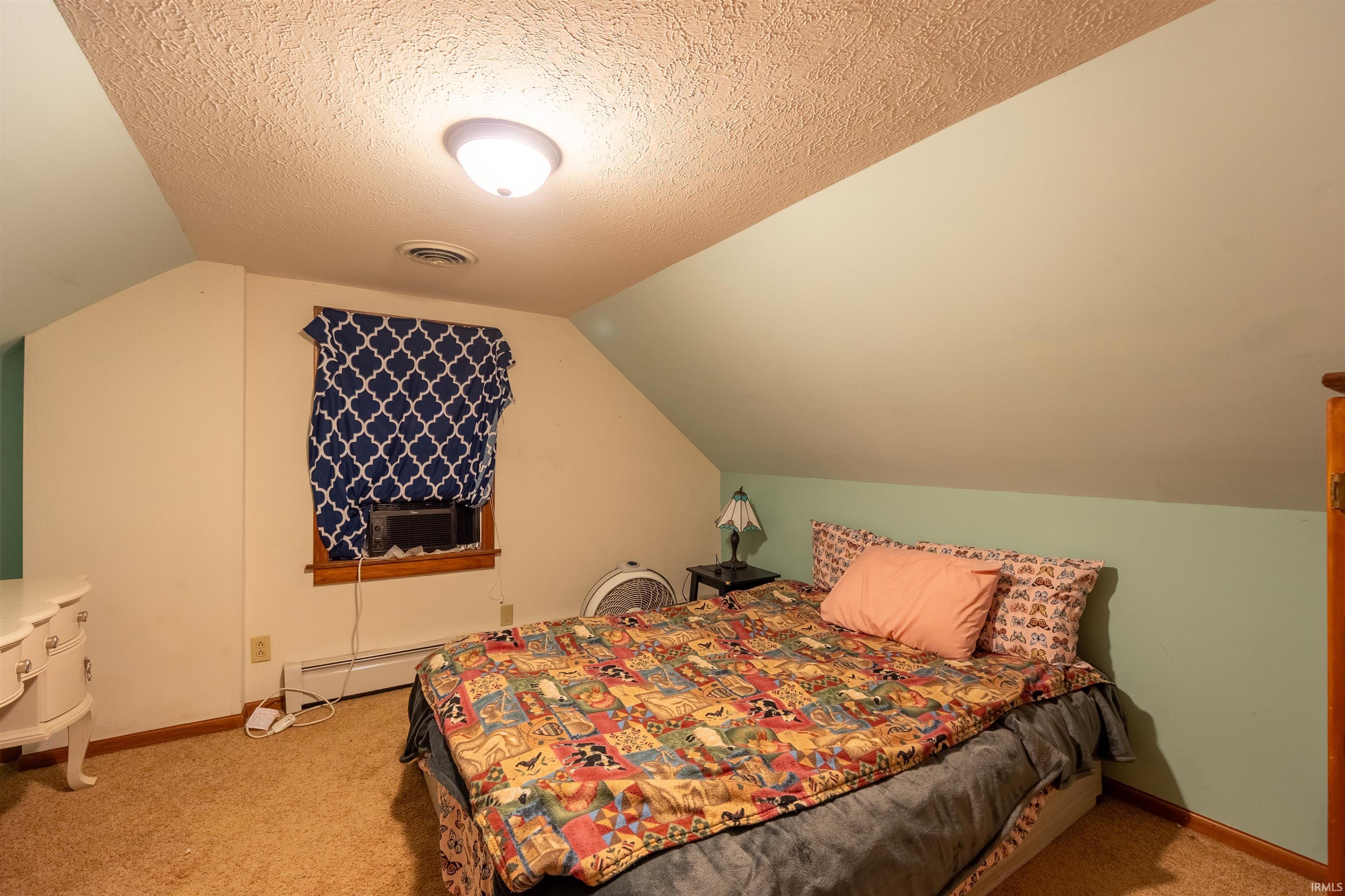 Carpeted room featuring sloped ceilings, a single window with wood trim, and a wall-mounted light fixture