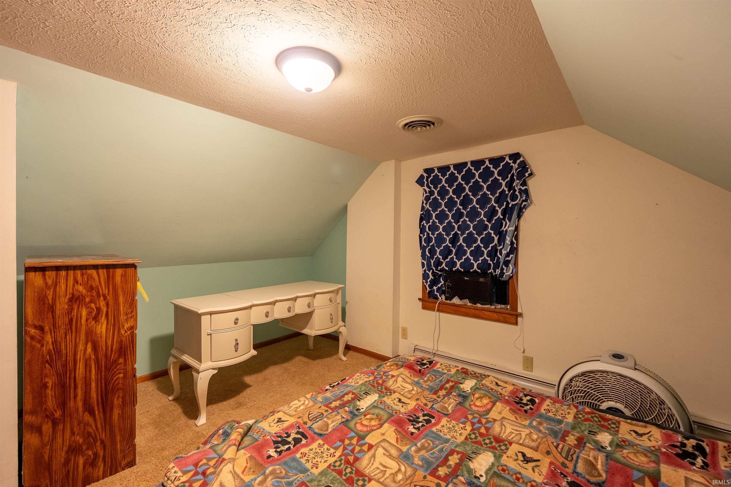 Attic space featuring sloped ceilings, recessed wall sections, a flush-mount ceiling light, and a window with wood trim