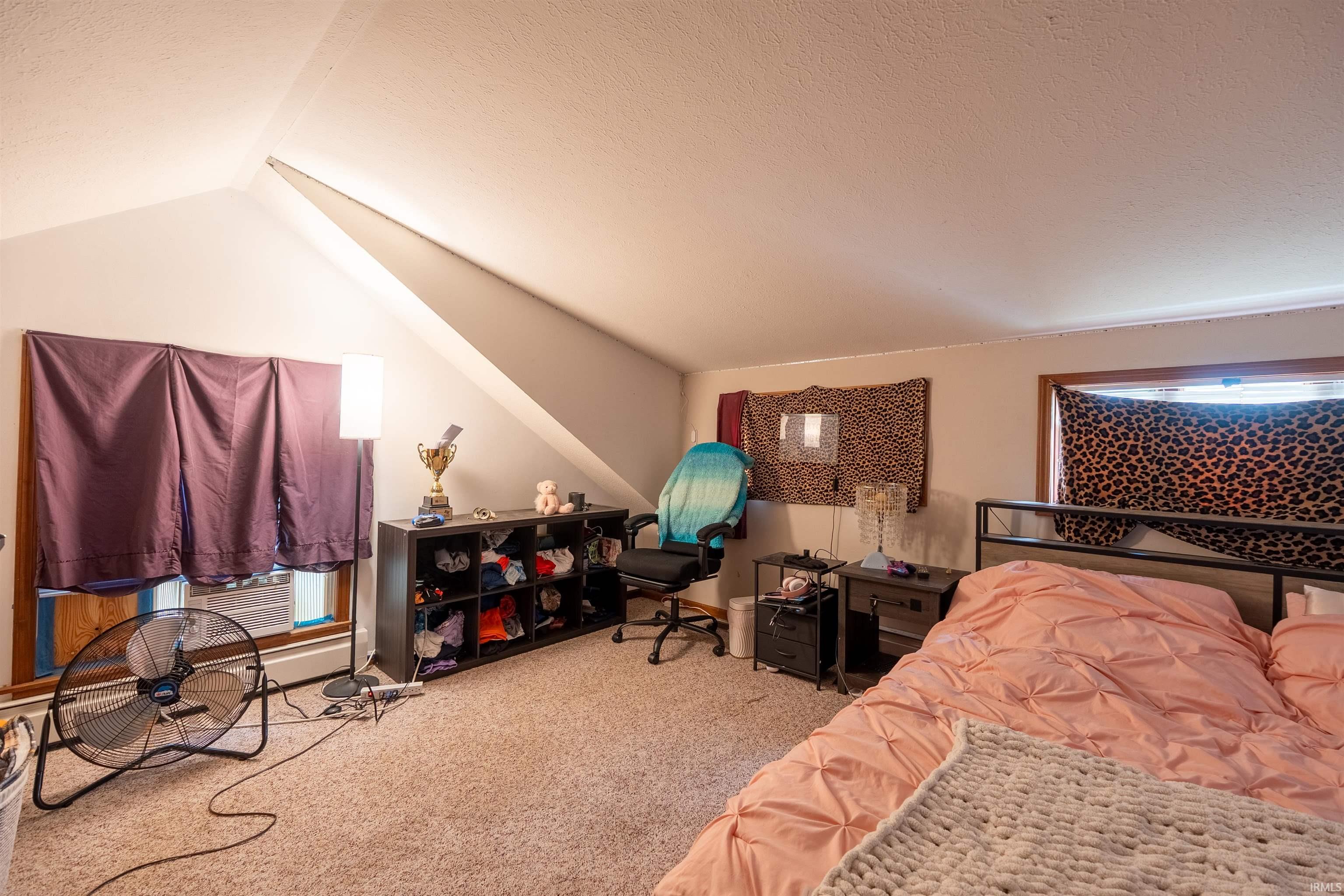 Carpeted room featuring sloped ceilings and multiple window openings with wood trim