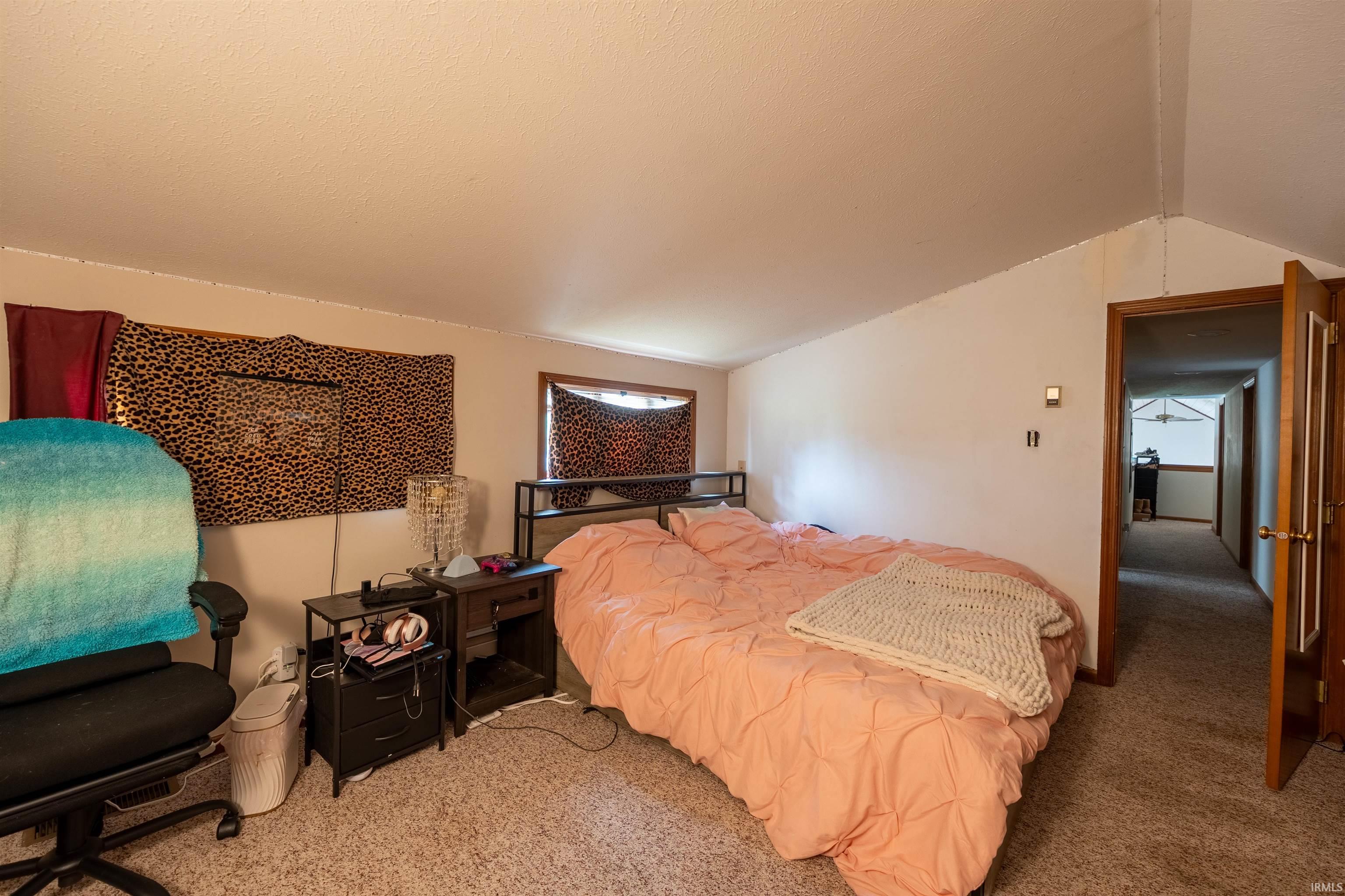 Carpeted room with sloped ceilings and white walls