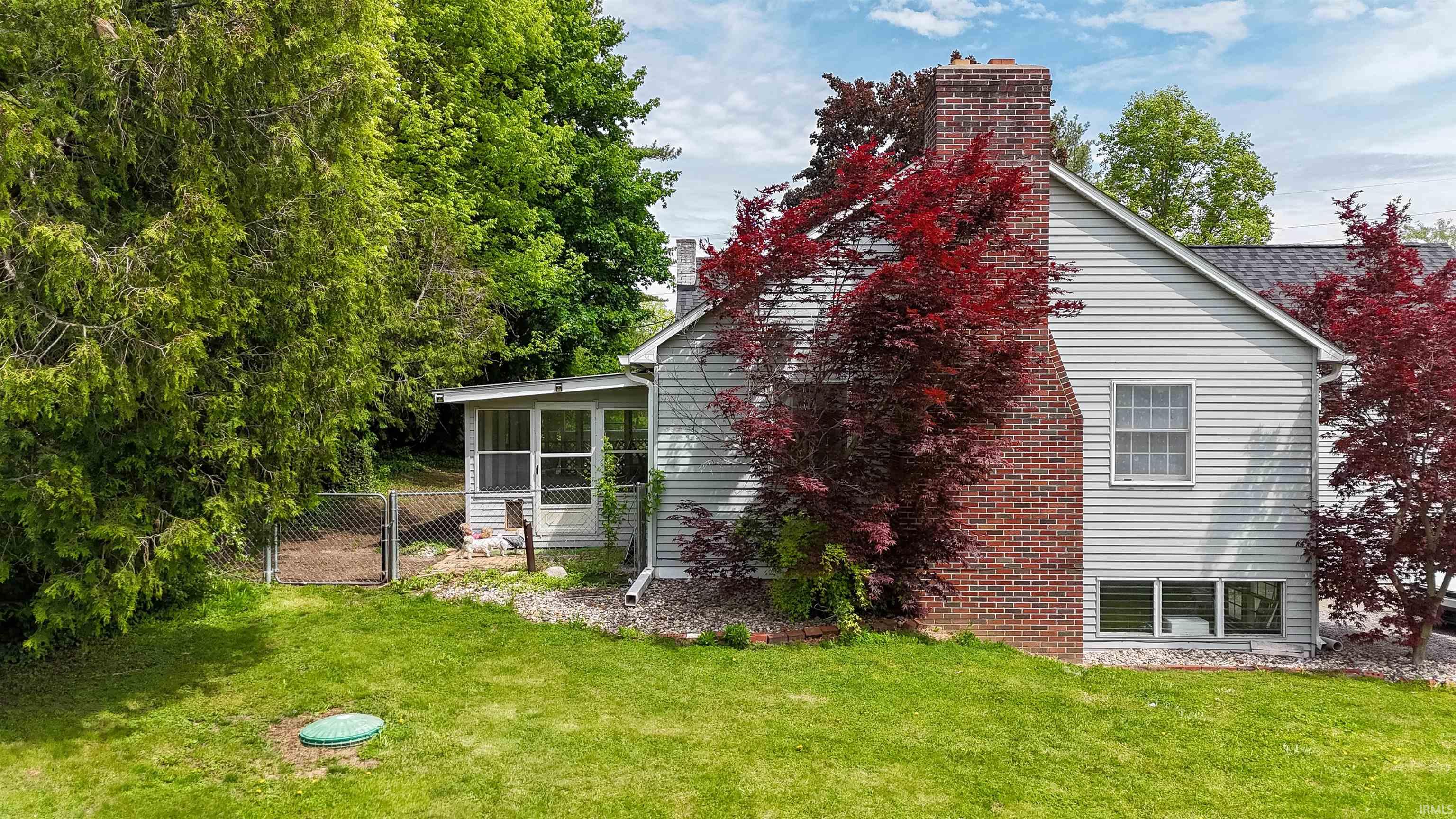 Expansive rear yard featuring green lawn and mature trees