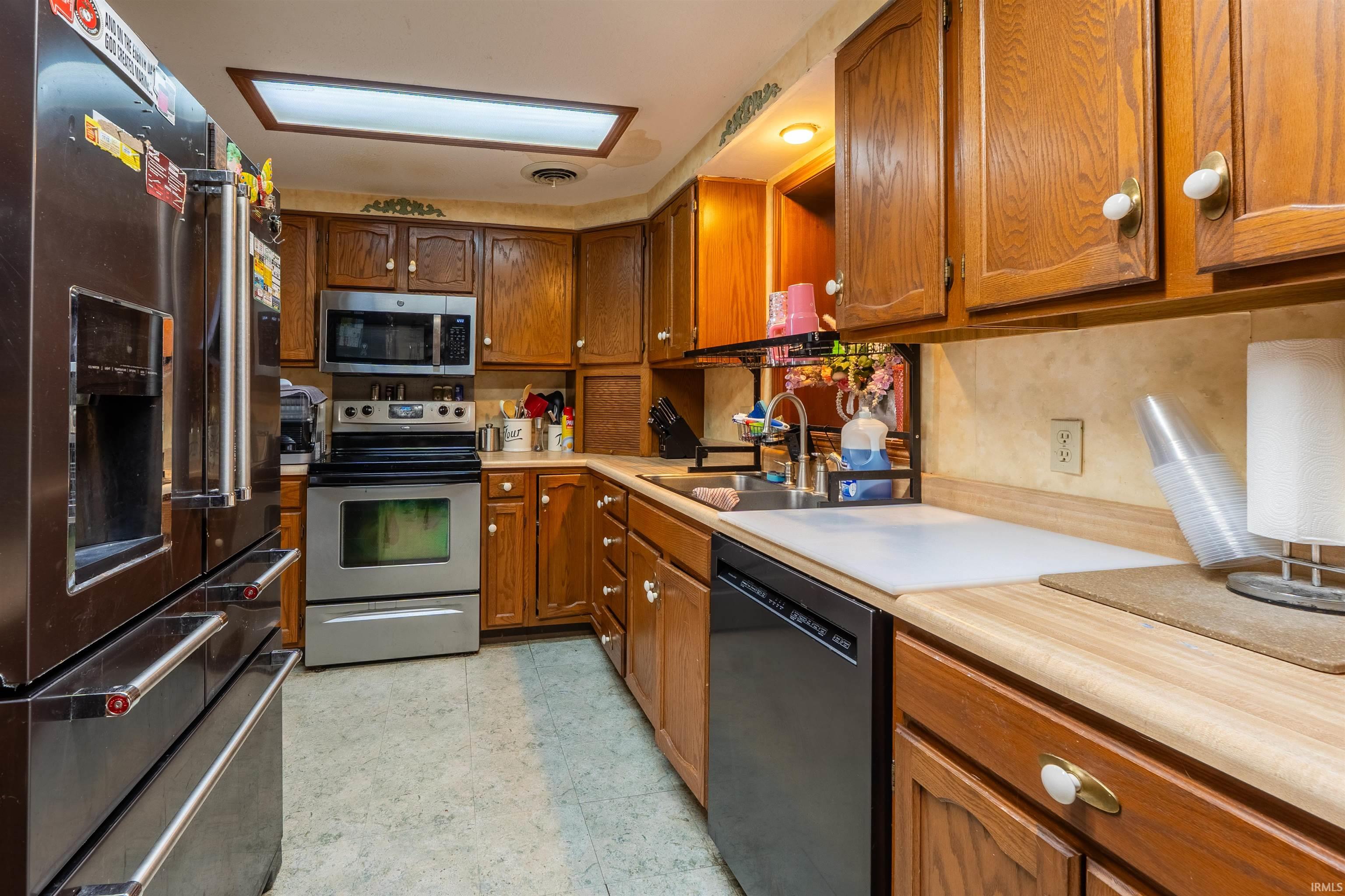 Kitchen featuring wood cabinetry, stainless steel appliances, a built-in microwave, and a double basin sink