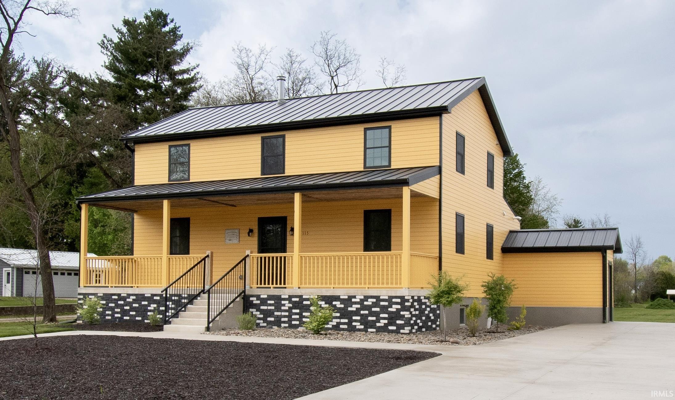 Two-story residence featuring yellow siding and black trim
