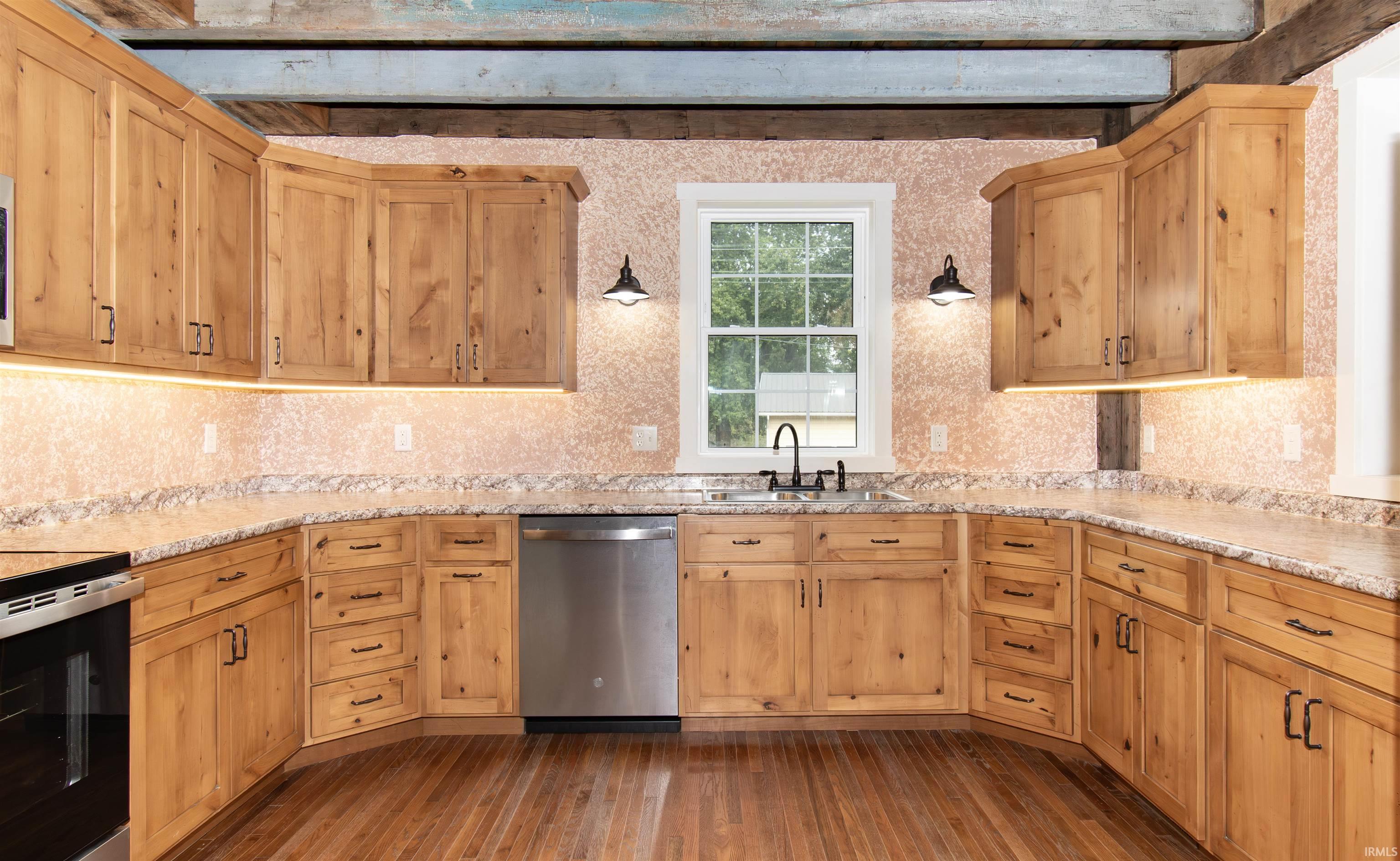 U-shaped kitchen featuring light wood cabinetry, stone-finish countertops, and wood-finish flooring