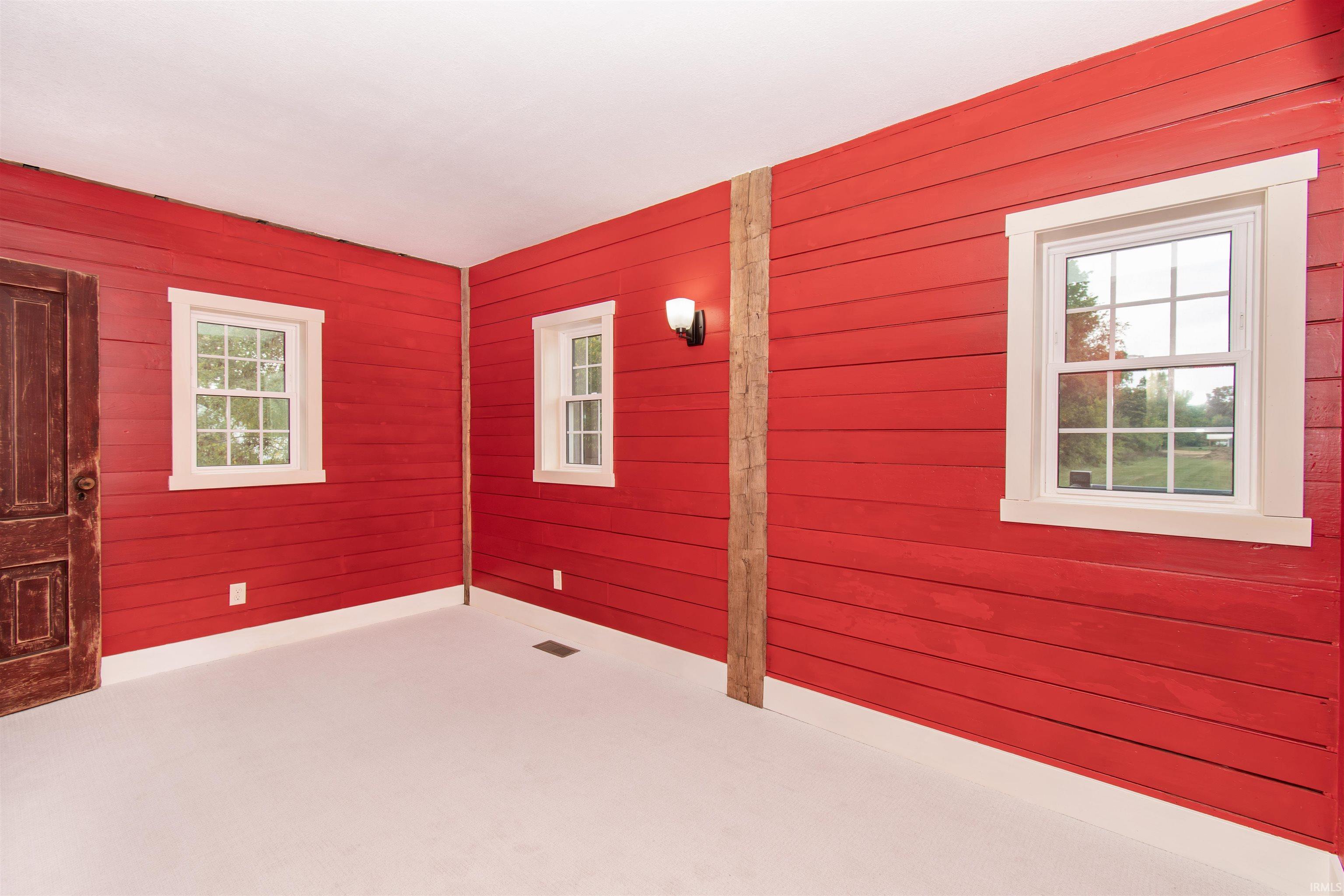 Interior space featuring red horizontal paneling, white trim around windows, and a prominent dark wood door