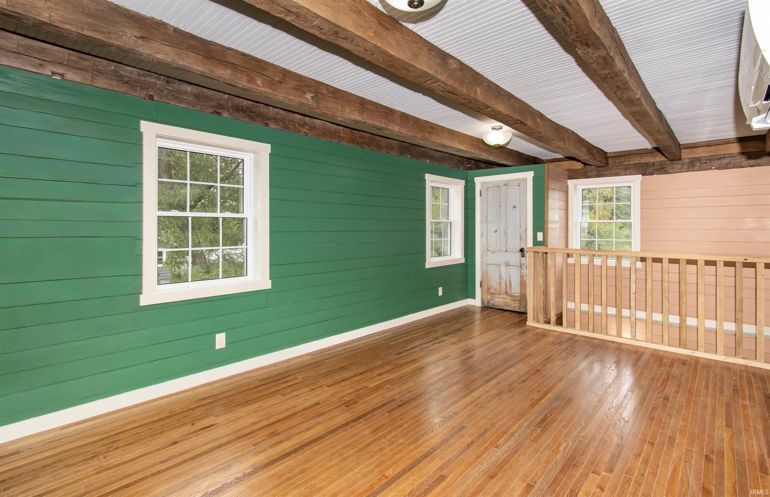 Exposed wood beams and wood-finish flooring characterize this room