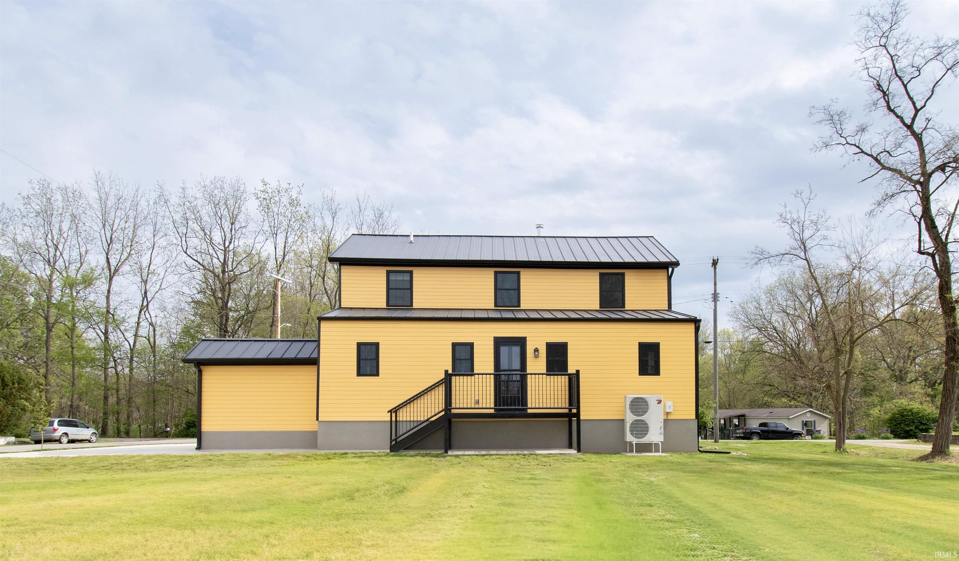 Contemporary yellow siding exterior with a black metal roof