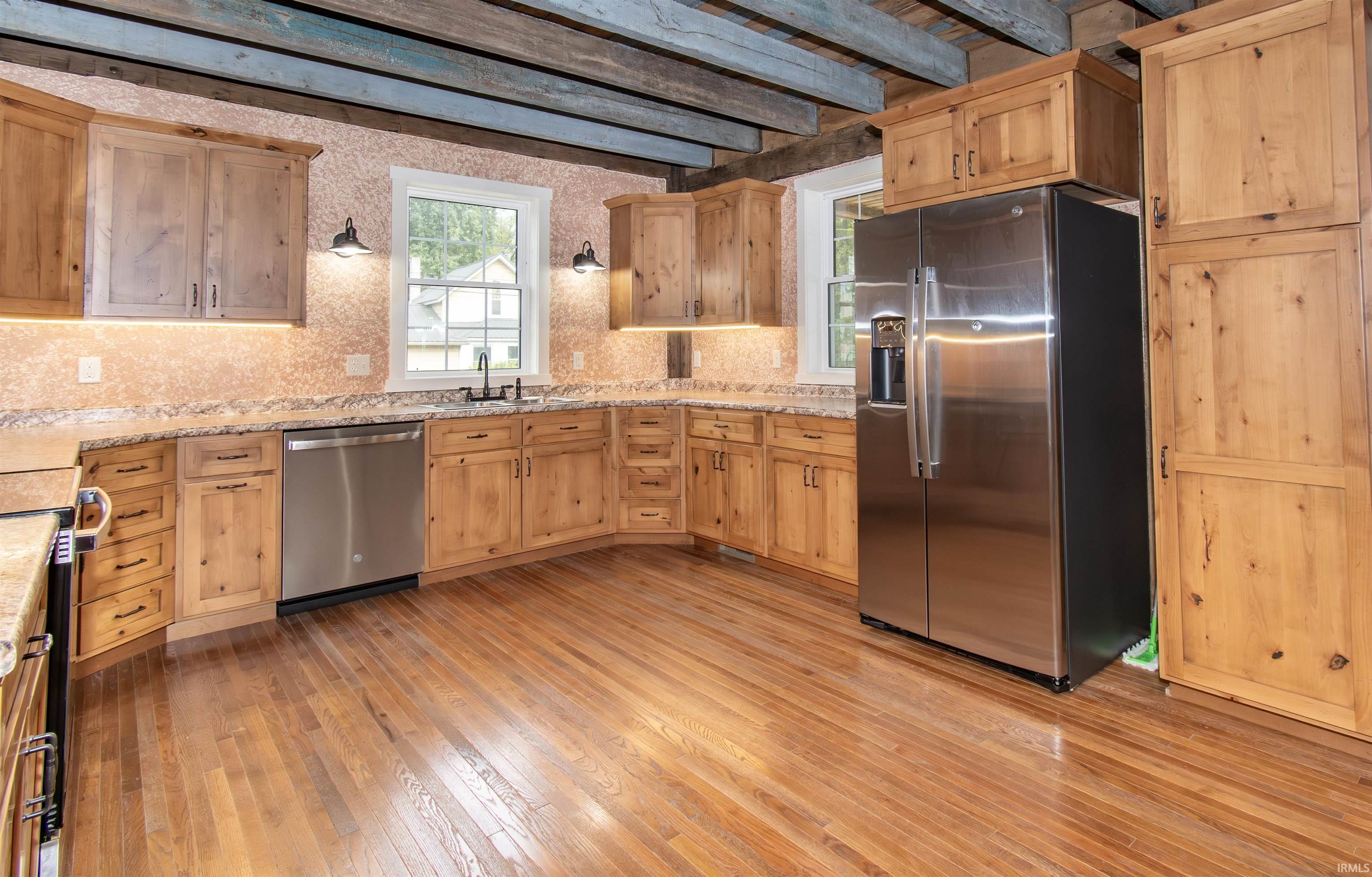 Kitchen featuring a stainless steel side-by-side refrigerator, under-cabinet lighting, and wood-finish flooring