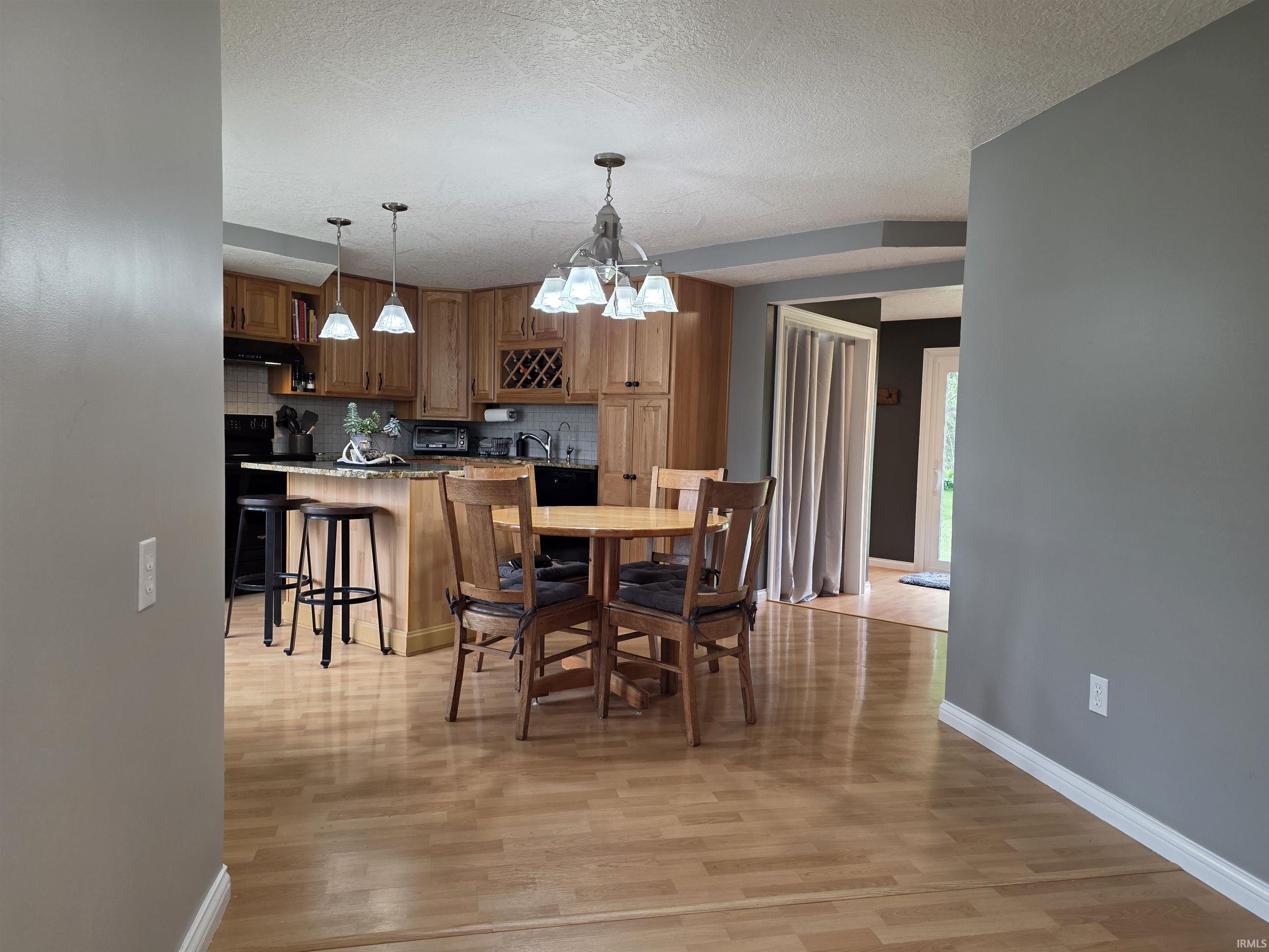 Kitchen and dining area featuring wood-finish flooring, recessed lighting, and a chandelier