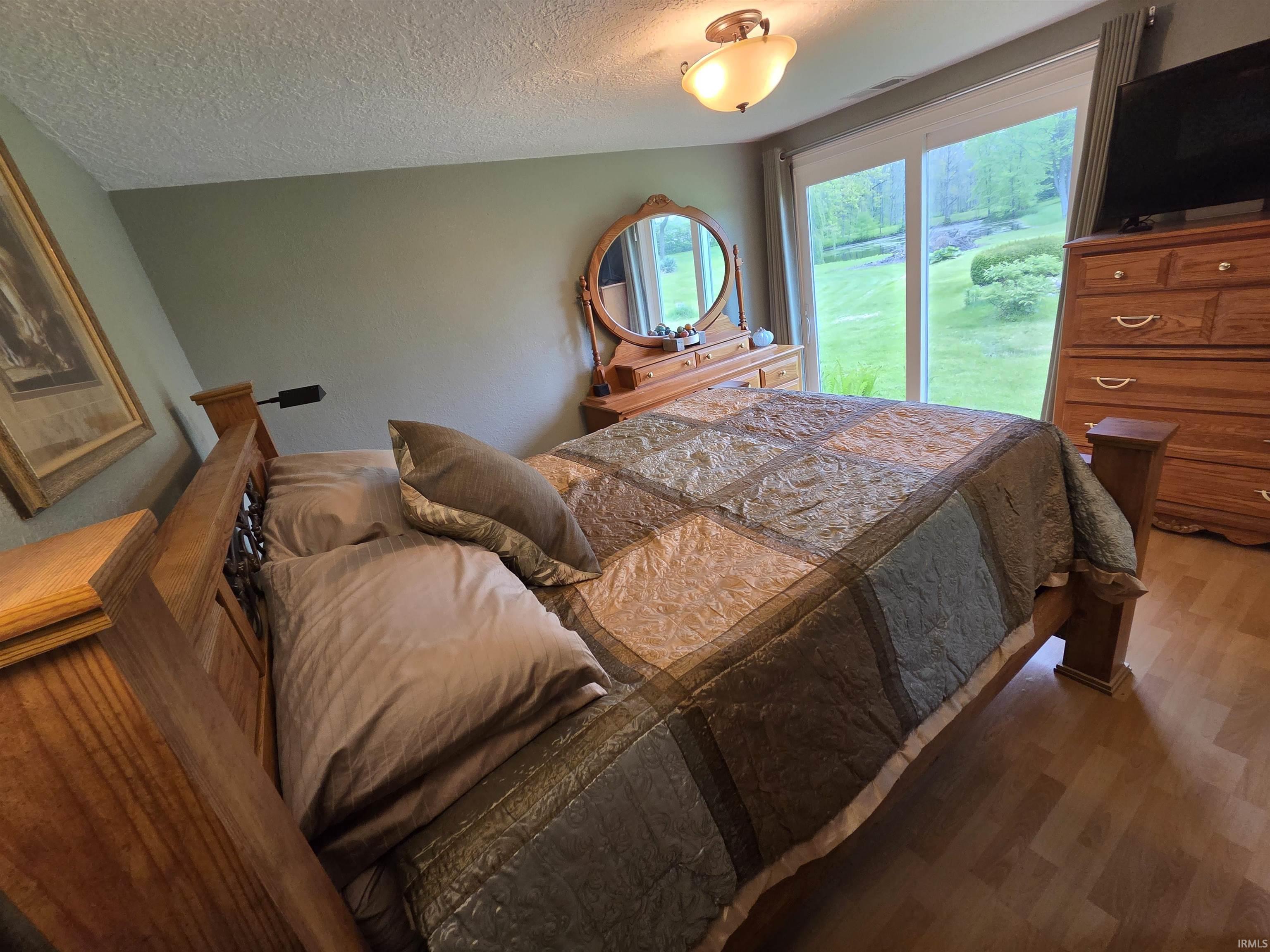 Spacious room featuring wood-finish flooring, a contemporary ceiling light fixture, and a sliding glass door providing direct outdoor access