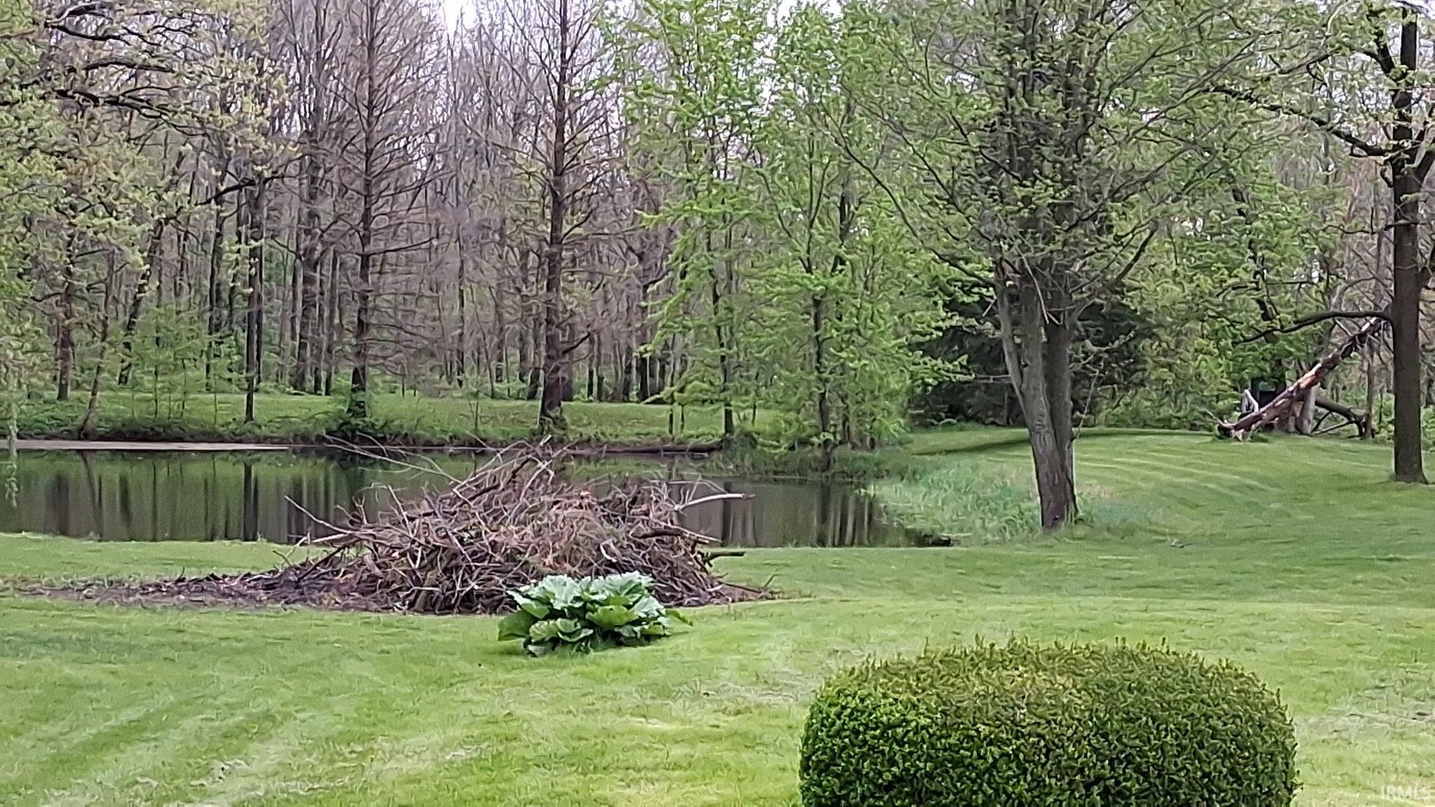 Expansive green lawn bordering a reflective pond, framed by mature trees