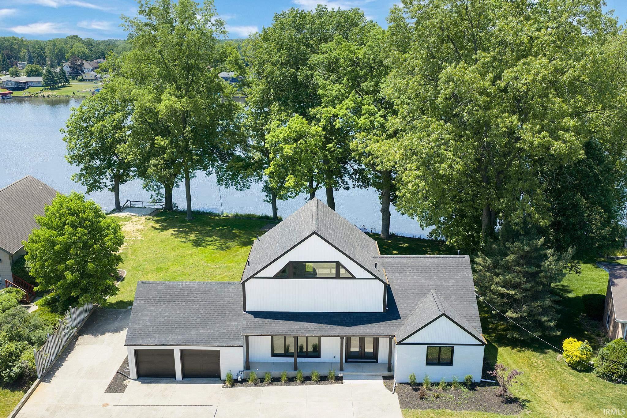 Modern lakefront residence featuring a two-car garage, dark trim, and a prominent gable roofline