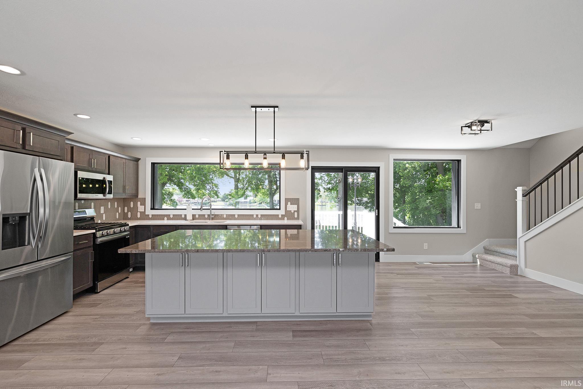 Spacious kitchen with a central island featuring a stone-finish countertop and light-toned cabinetry