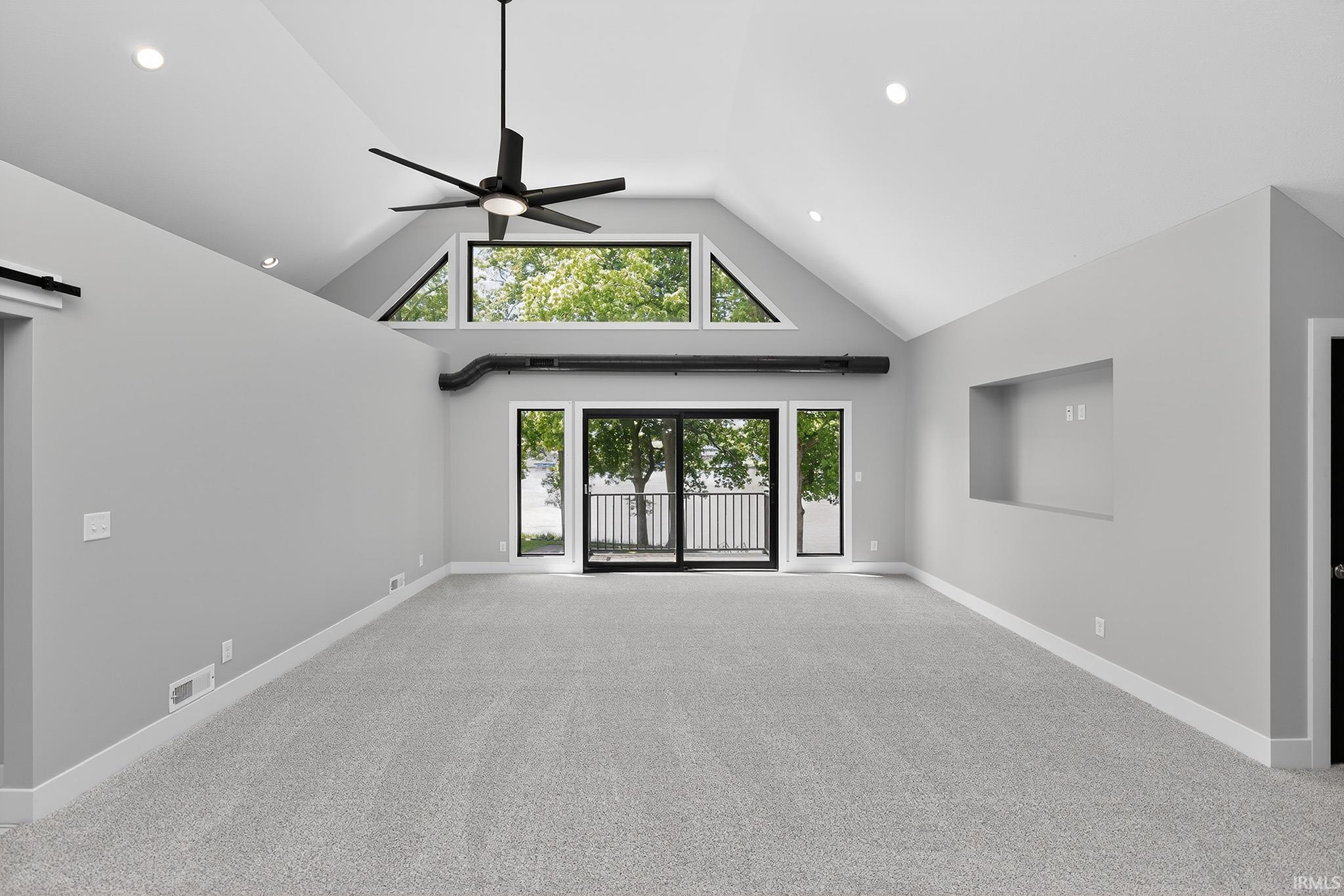 Spacious room featuring vaulted ceilings, light gray carpeting, and white trim