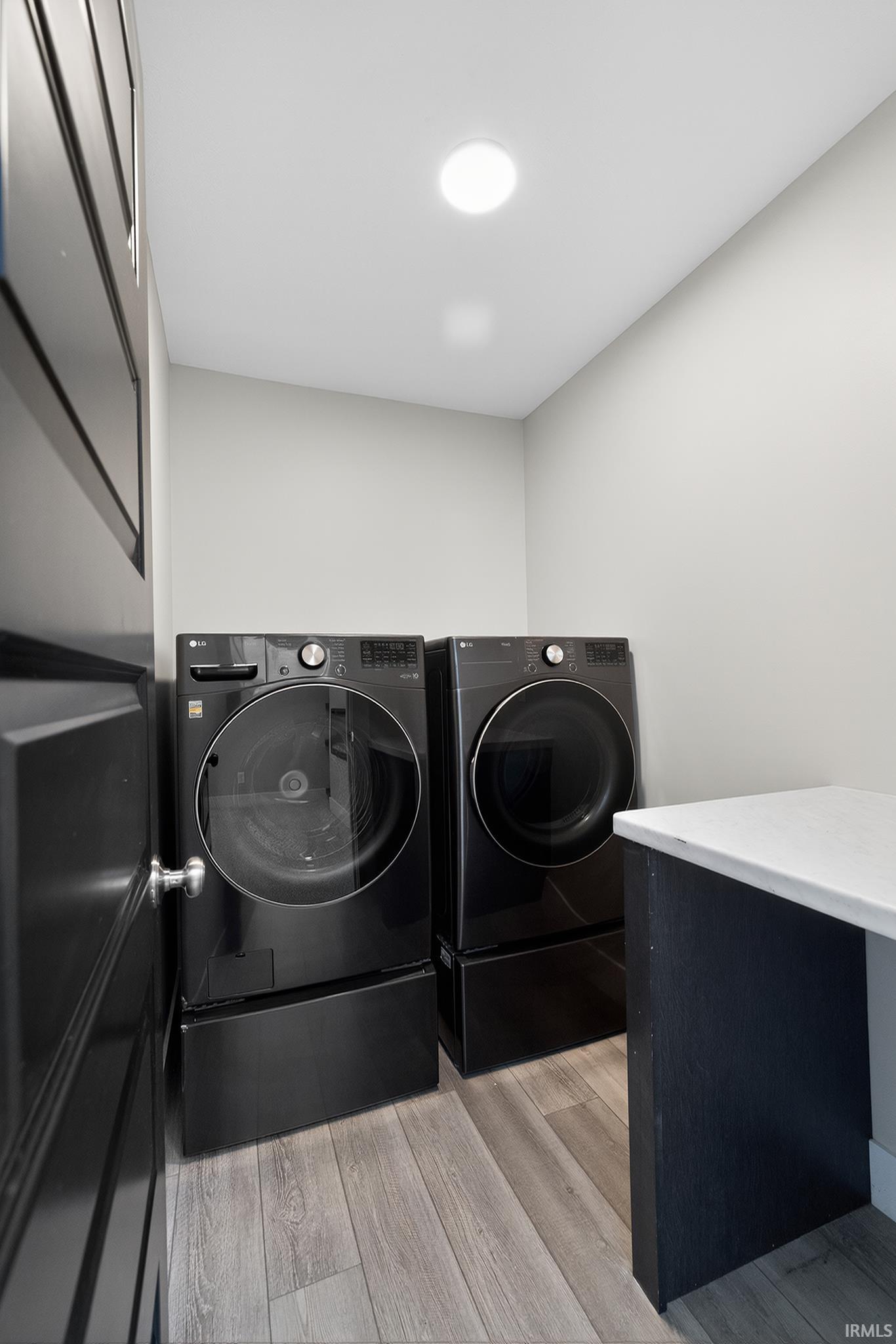 Dedicated laundry area featuring wood-finish flooring and a built-in countertop with a light-toned surface