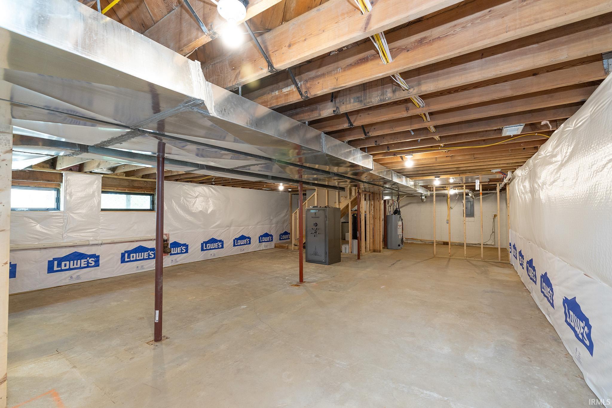Unfinished basement featuring exposed wood joists, concrete flooring, and perimeter insulation